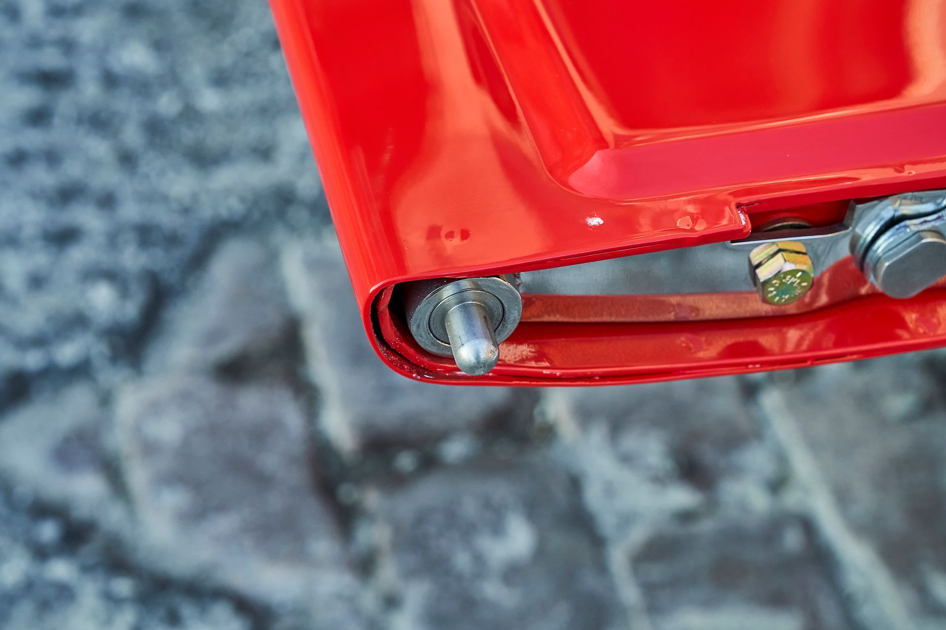 A close up of a red object with nuts and bolts on it.