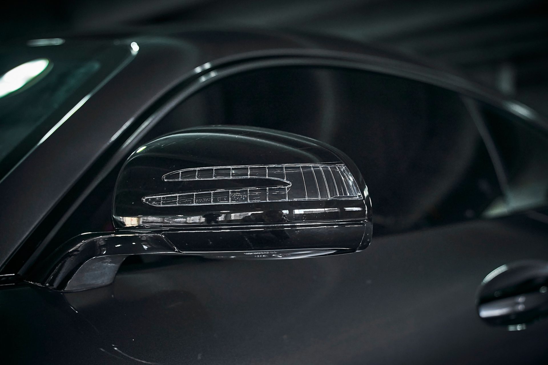A close up of a side view mirror on a black car.