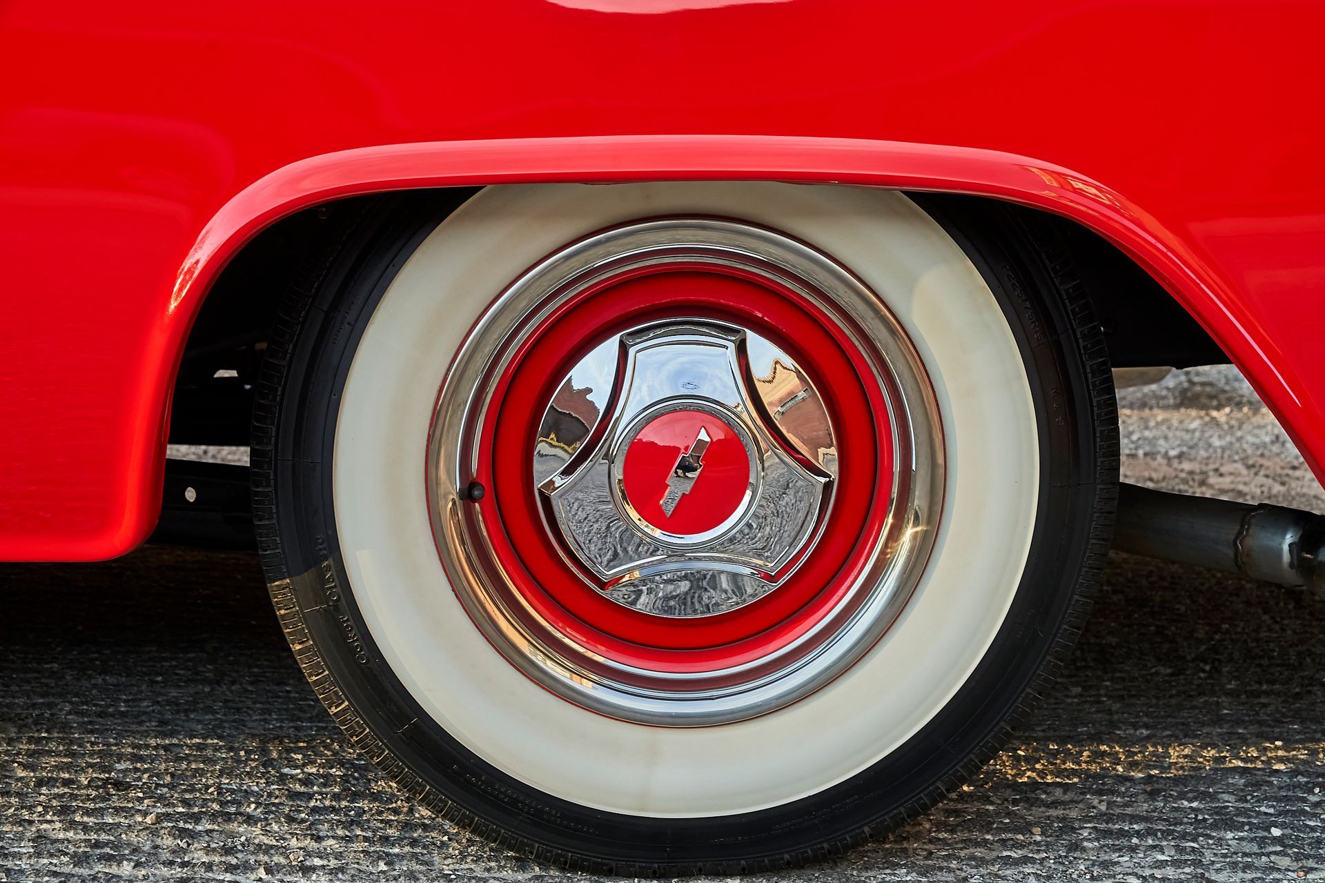 A close up of a red car wheel with white tires