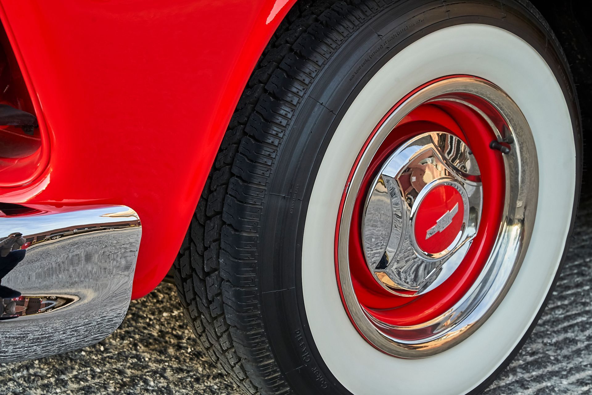 A close up of a red car wheel with white tires