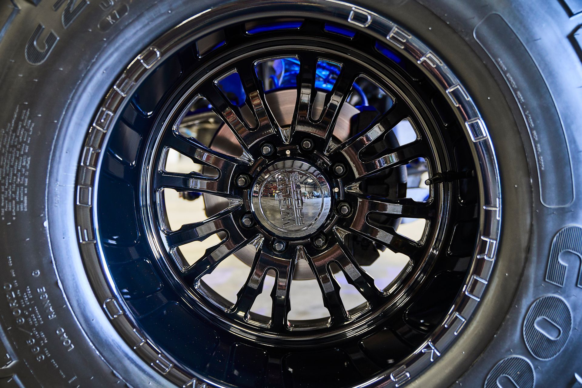 A close up of a black wheel with a tire in the background