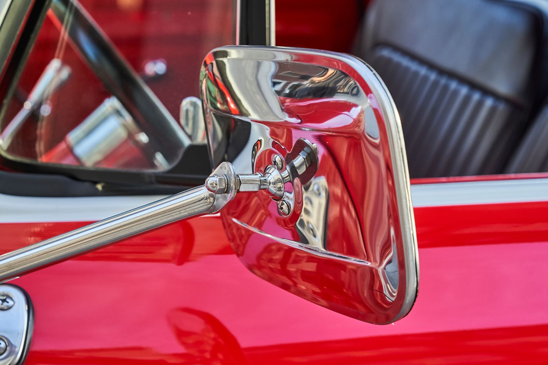 A close up of a red car 's side view mirror