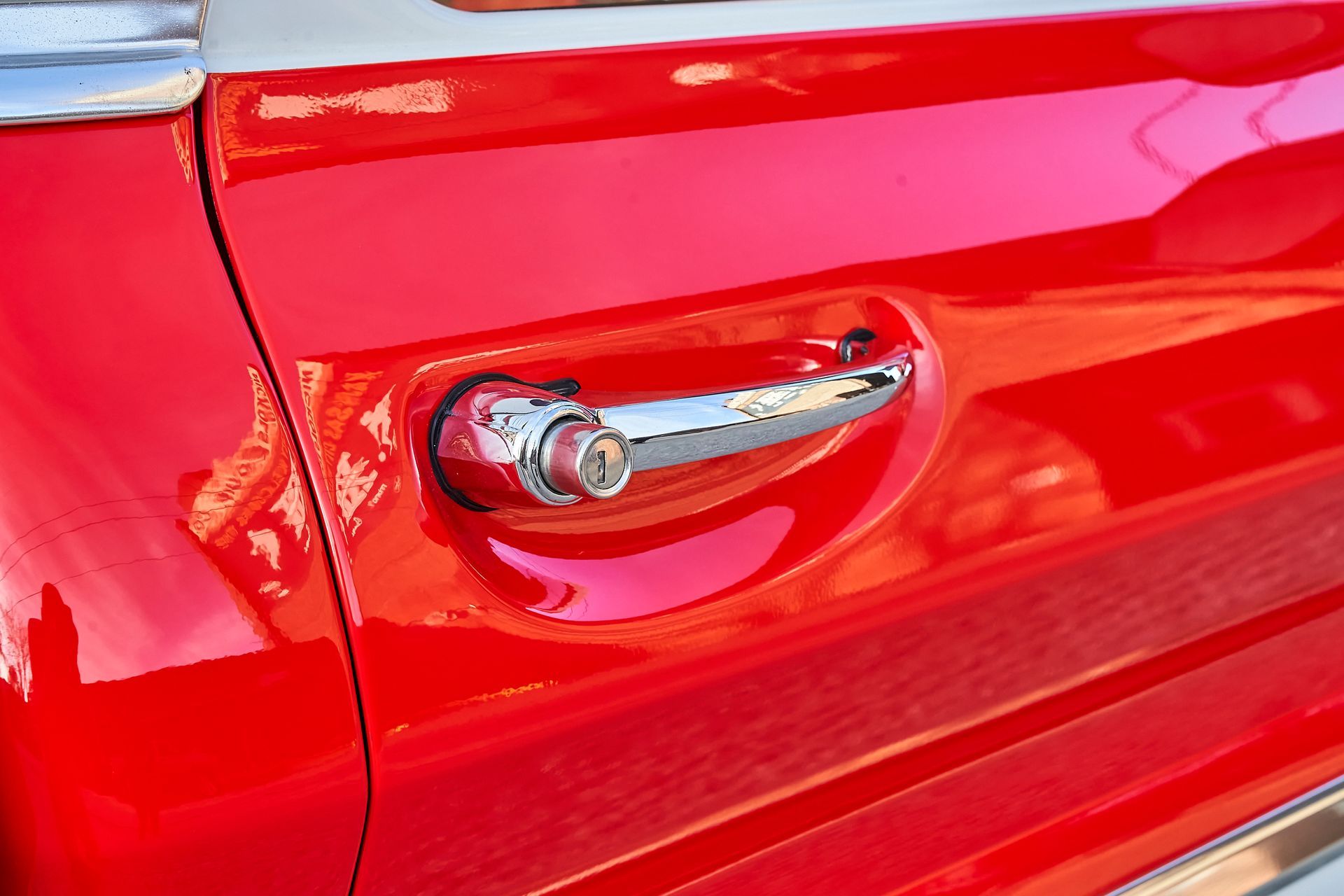 A close up of a red car door with a chrome handle.