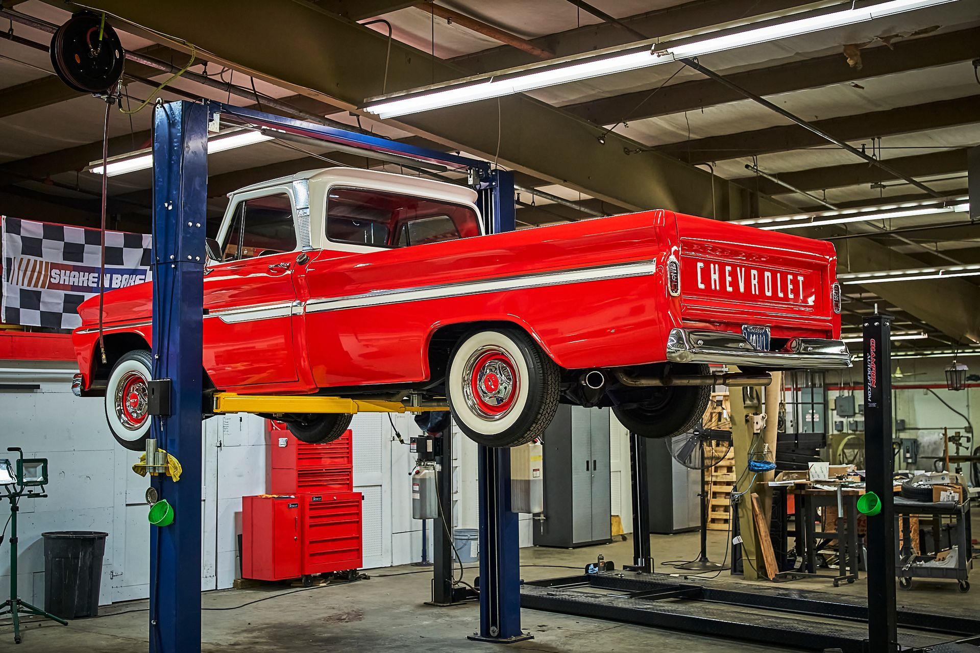 A red truck is sitting on a lift in a garage.