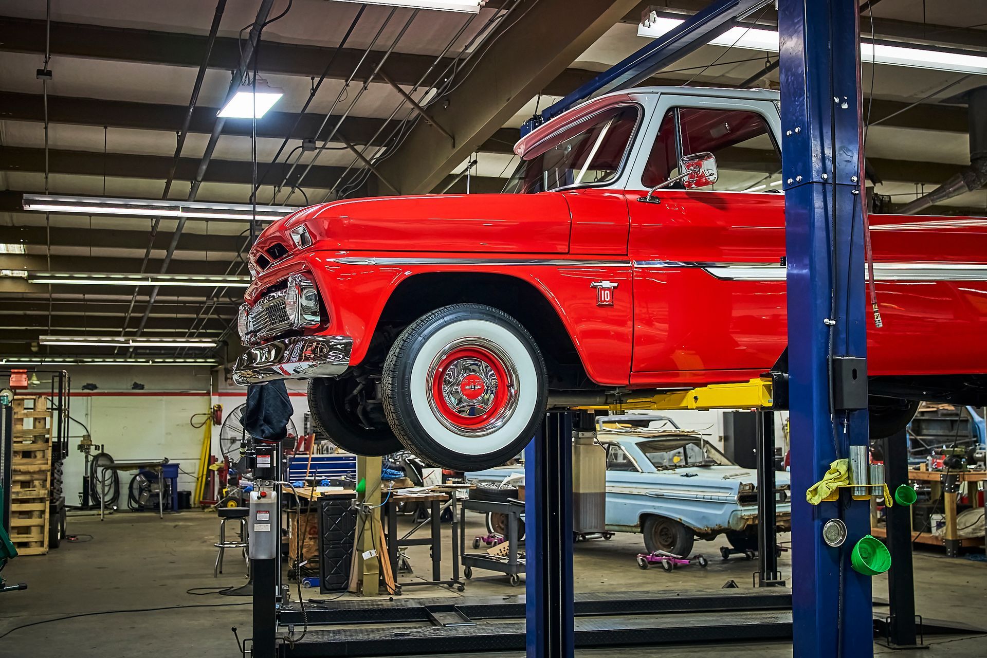 A red truck is on a lift in a garage.