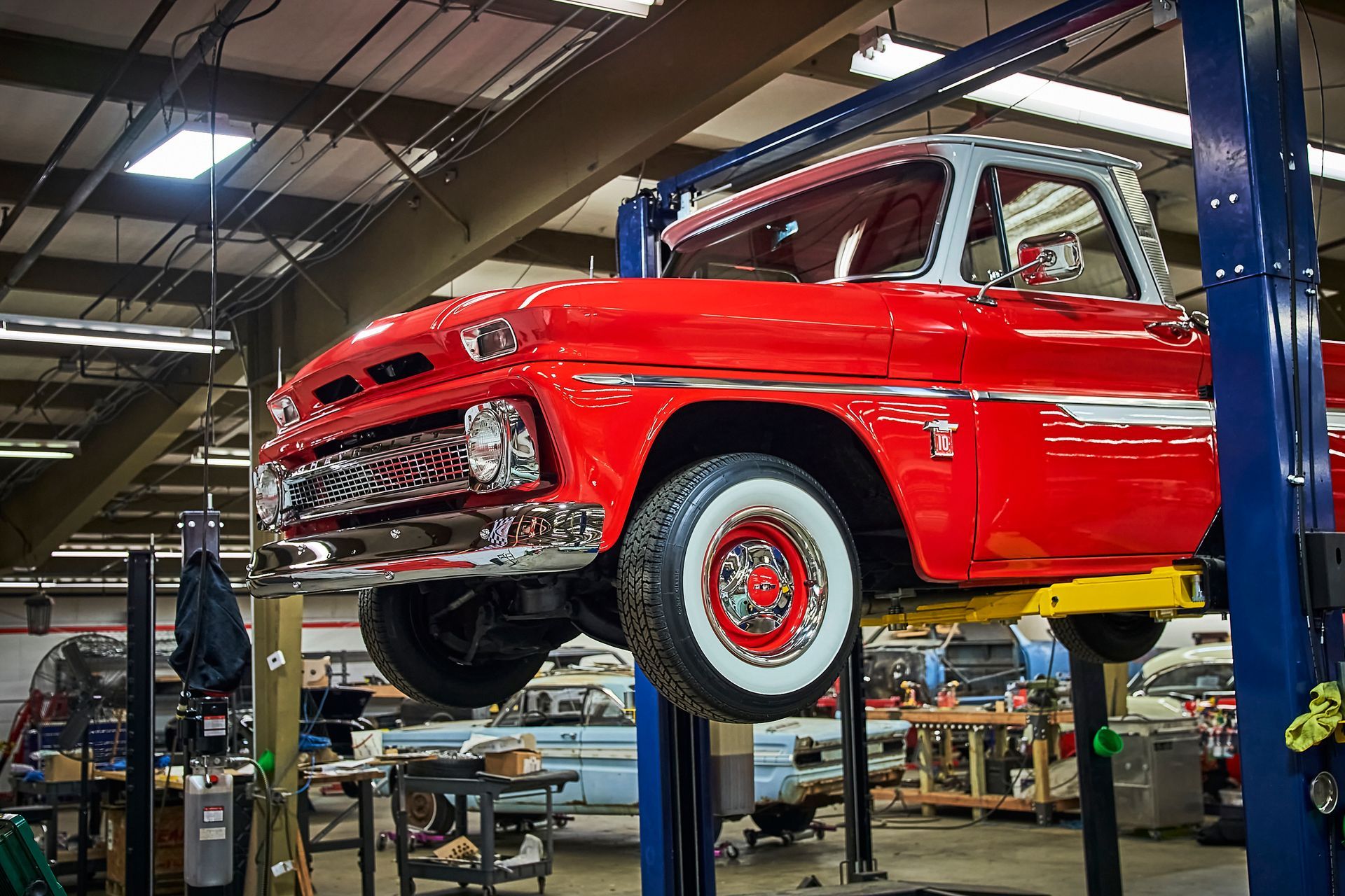 A red truck is sitting on a lift in a garage.