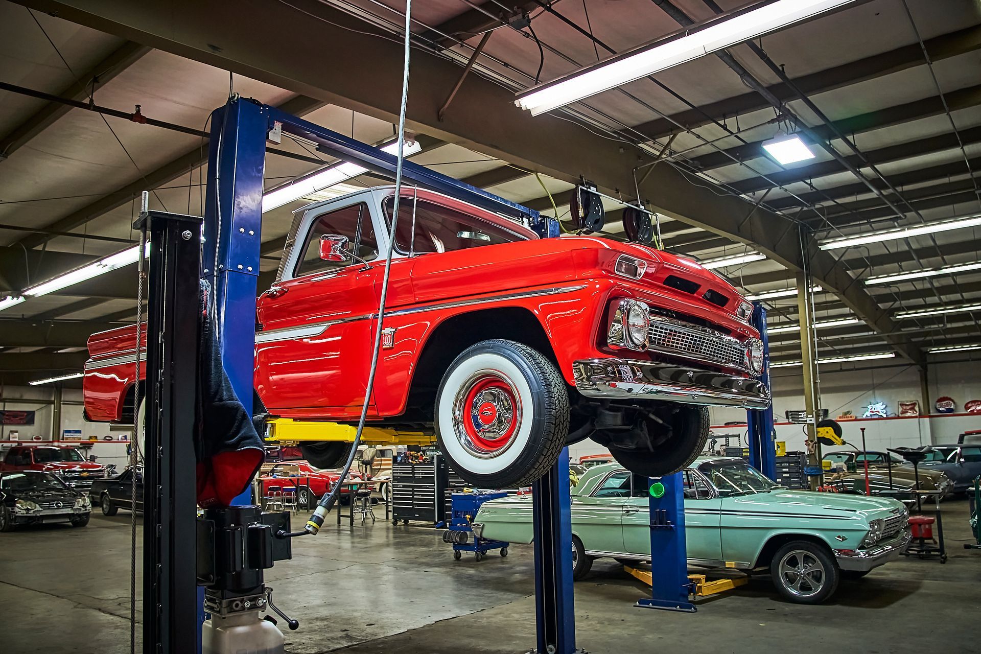 A red truck is on a lift in a garage.