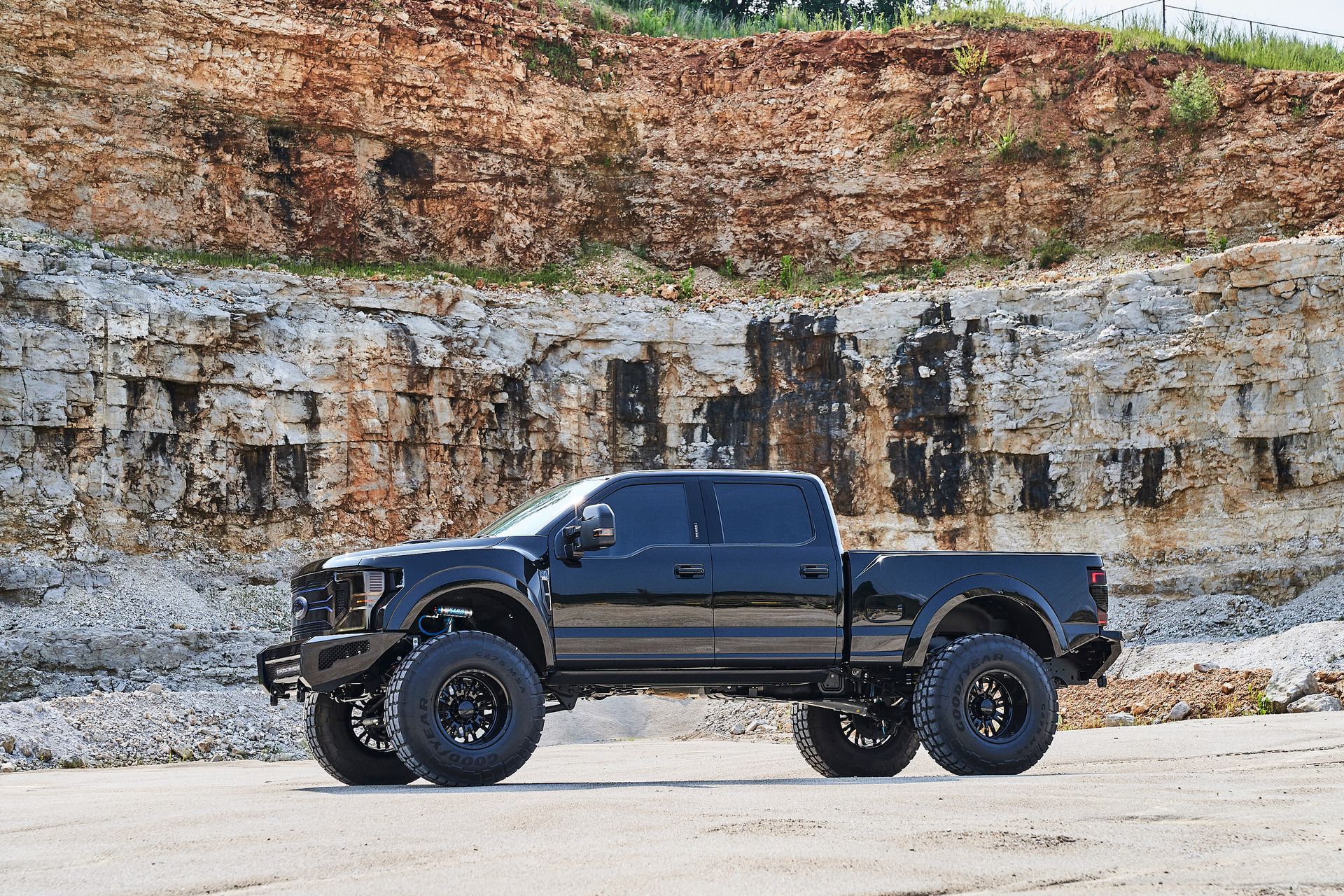 A black pickup truck is parked in front of a large rock formation.
