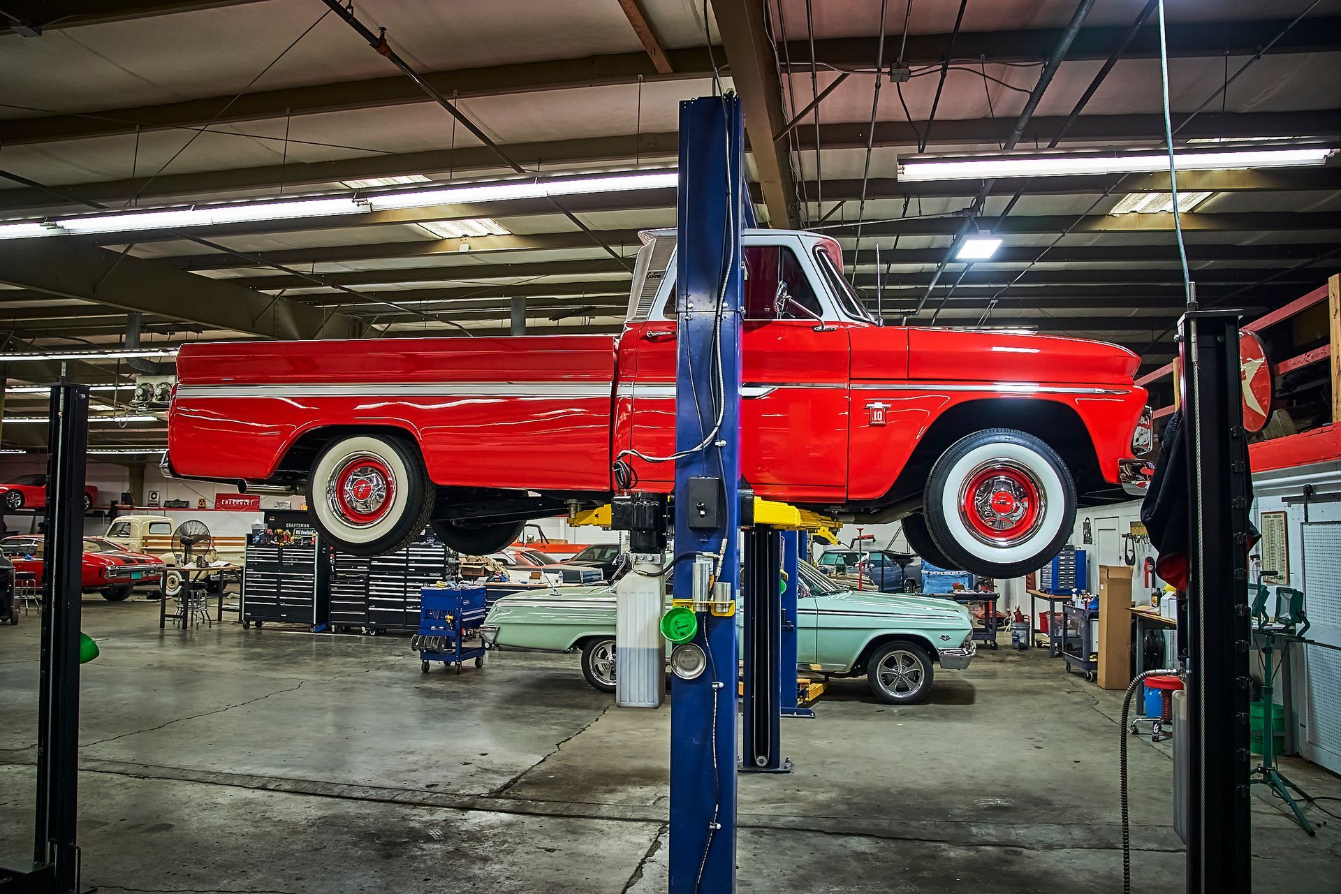 A red truck is on a lift in a garage.