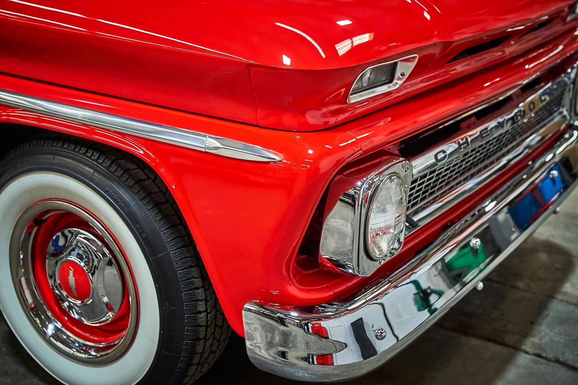 A red truck with white tires and chrome trim is parked in a garage.