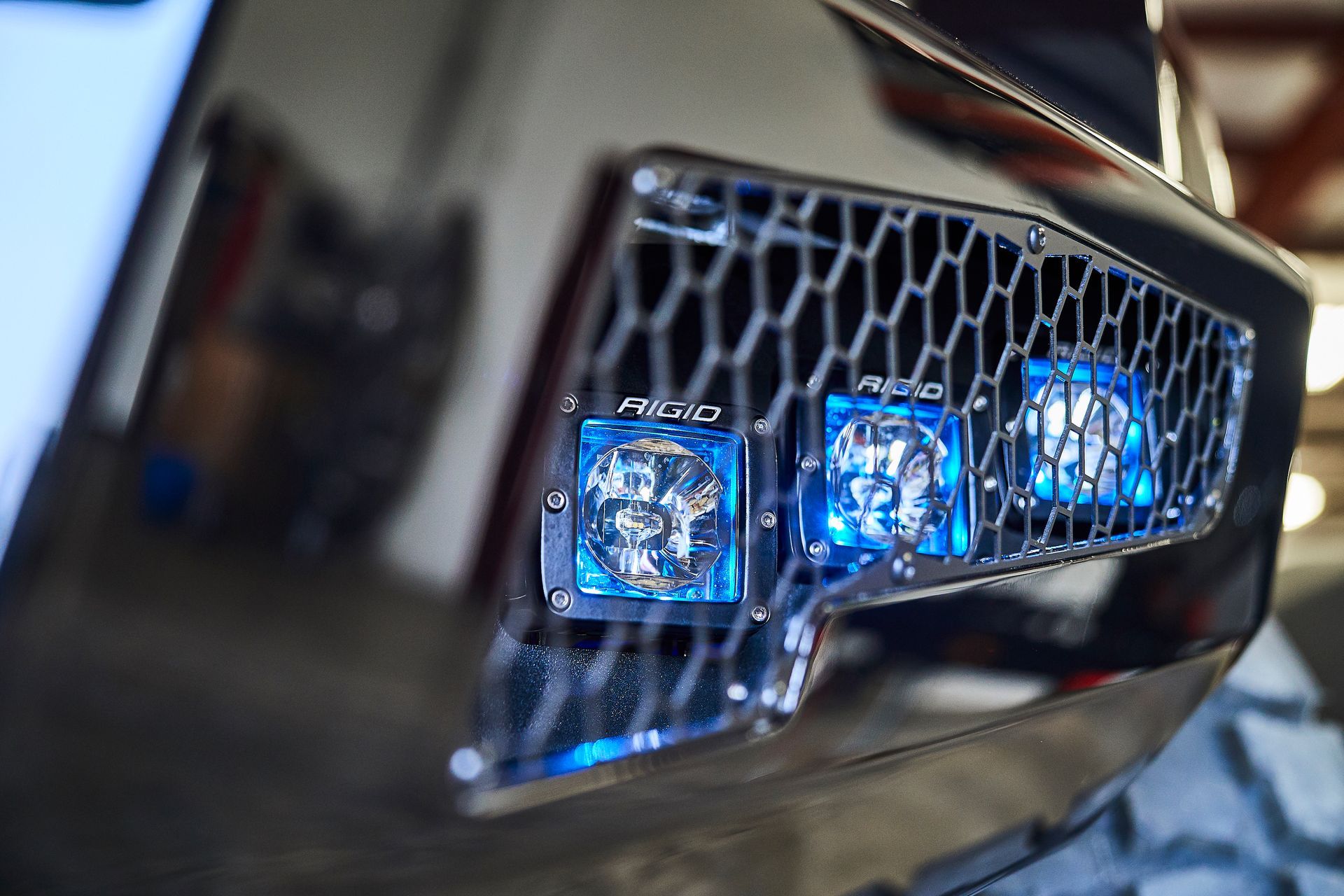 A close up of a grille on a car with blue lights on it.