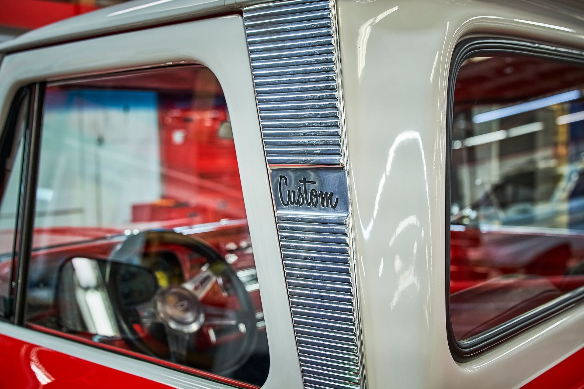 A close up of a red and white truck with a steering wheel in a garage.