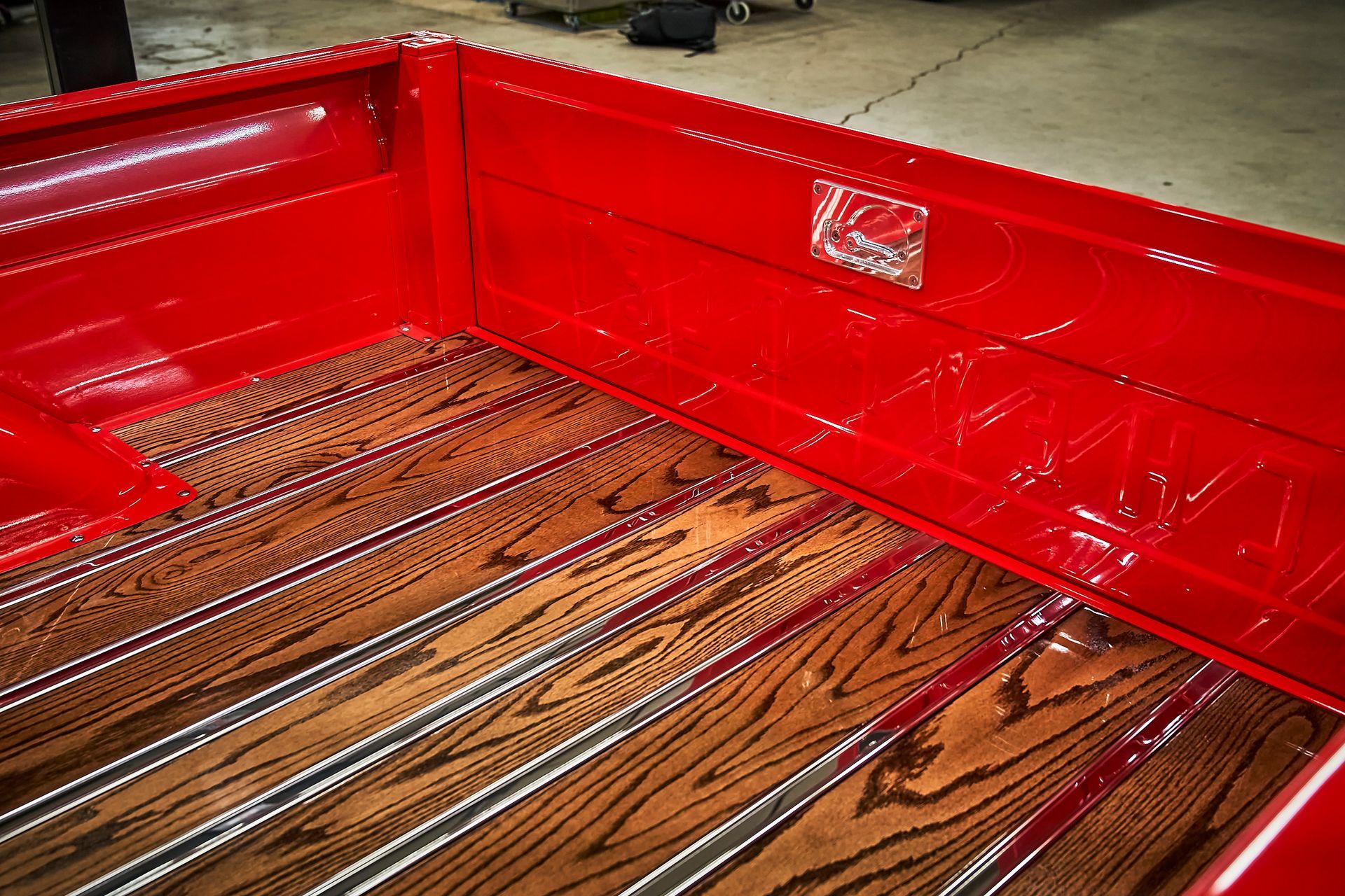 The back of a red truck with a wooden bed.