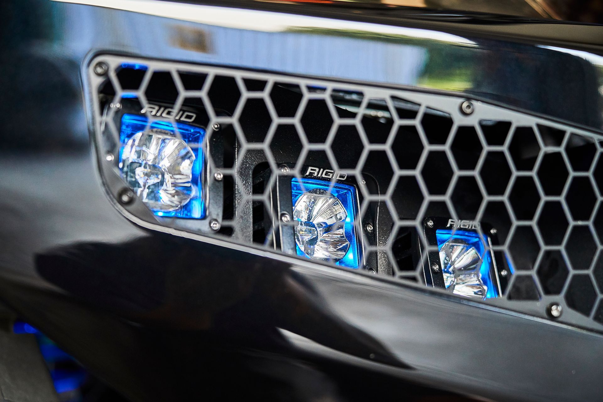 A close up of a honeycomb grille on a car with blue lights.
