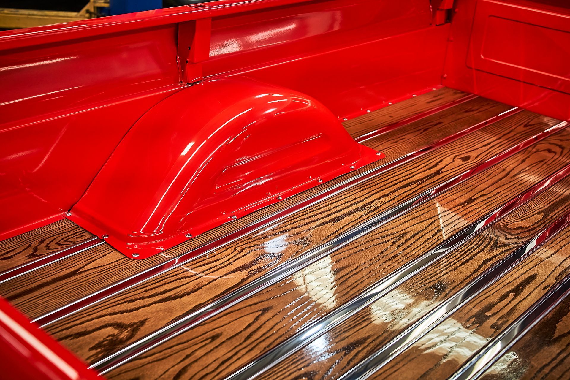 The back of a red truck with a wooden bed.