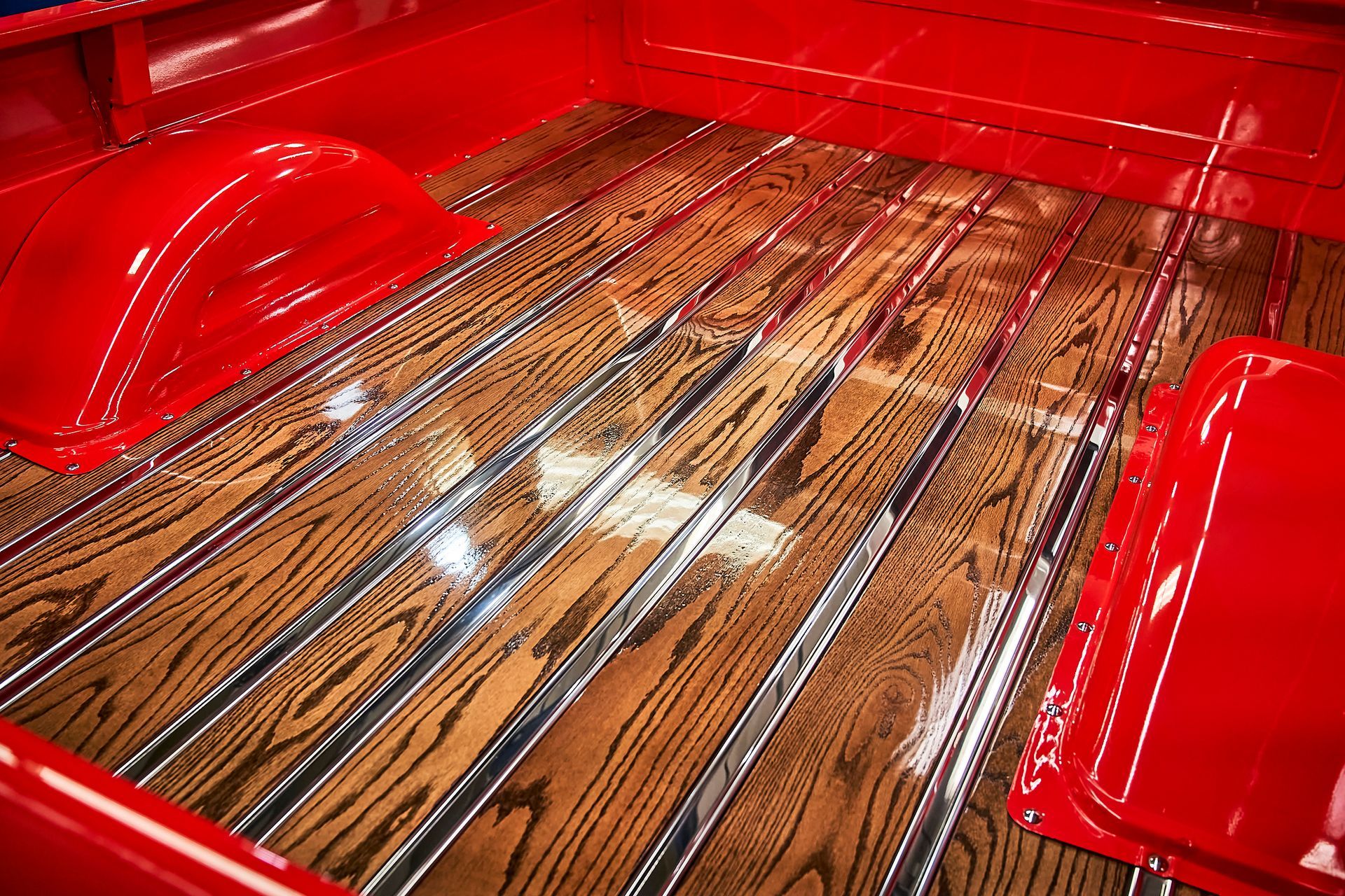 The back of a red truck with a wooden floor.