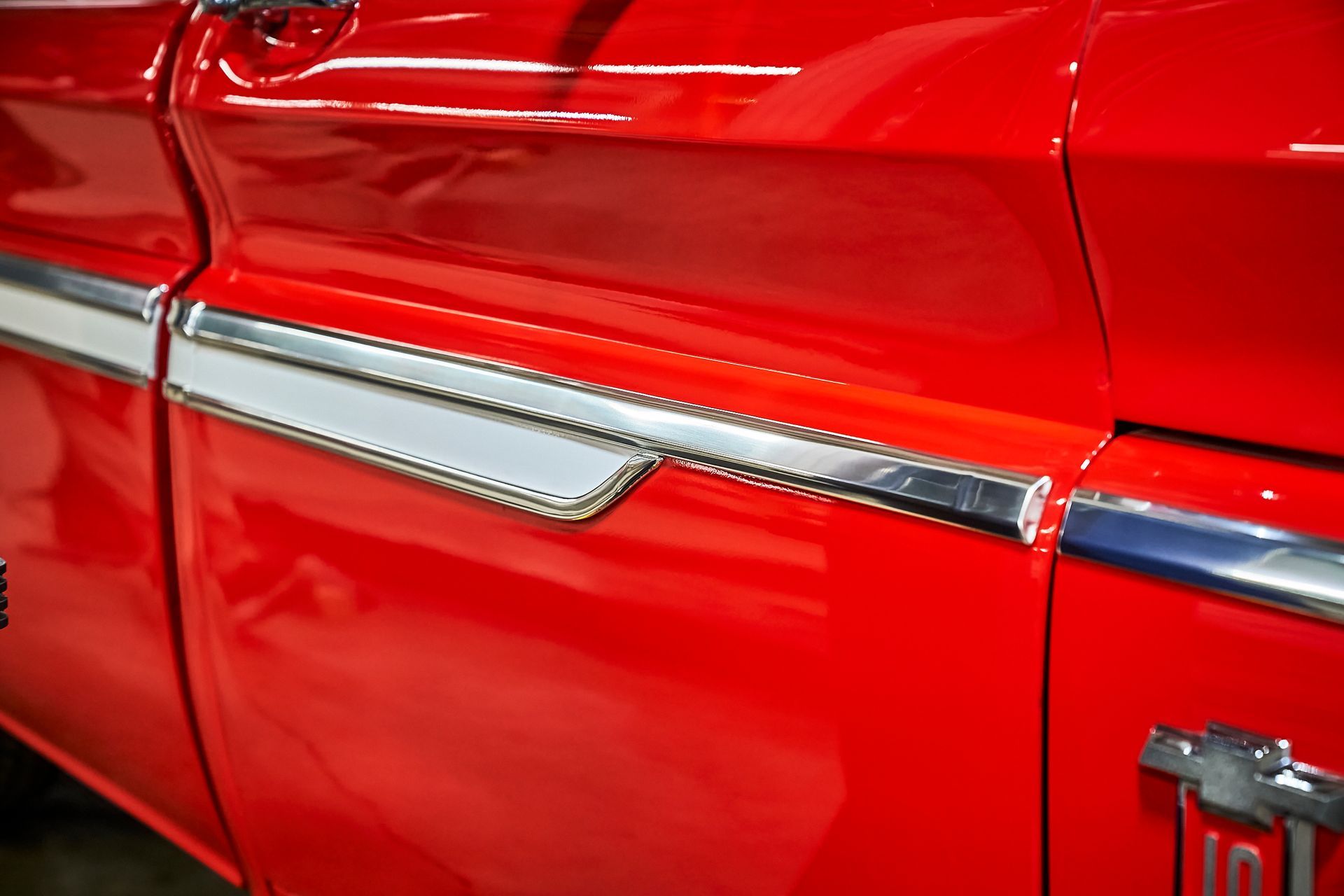 A close up of the side of a red truck with chrome trim.