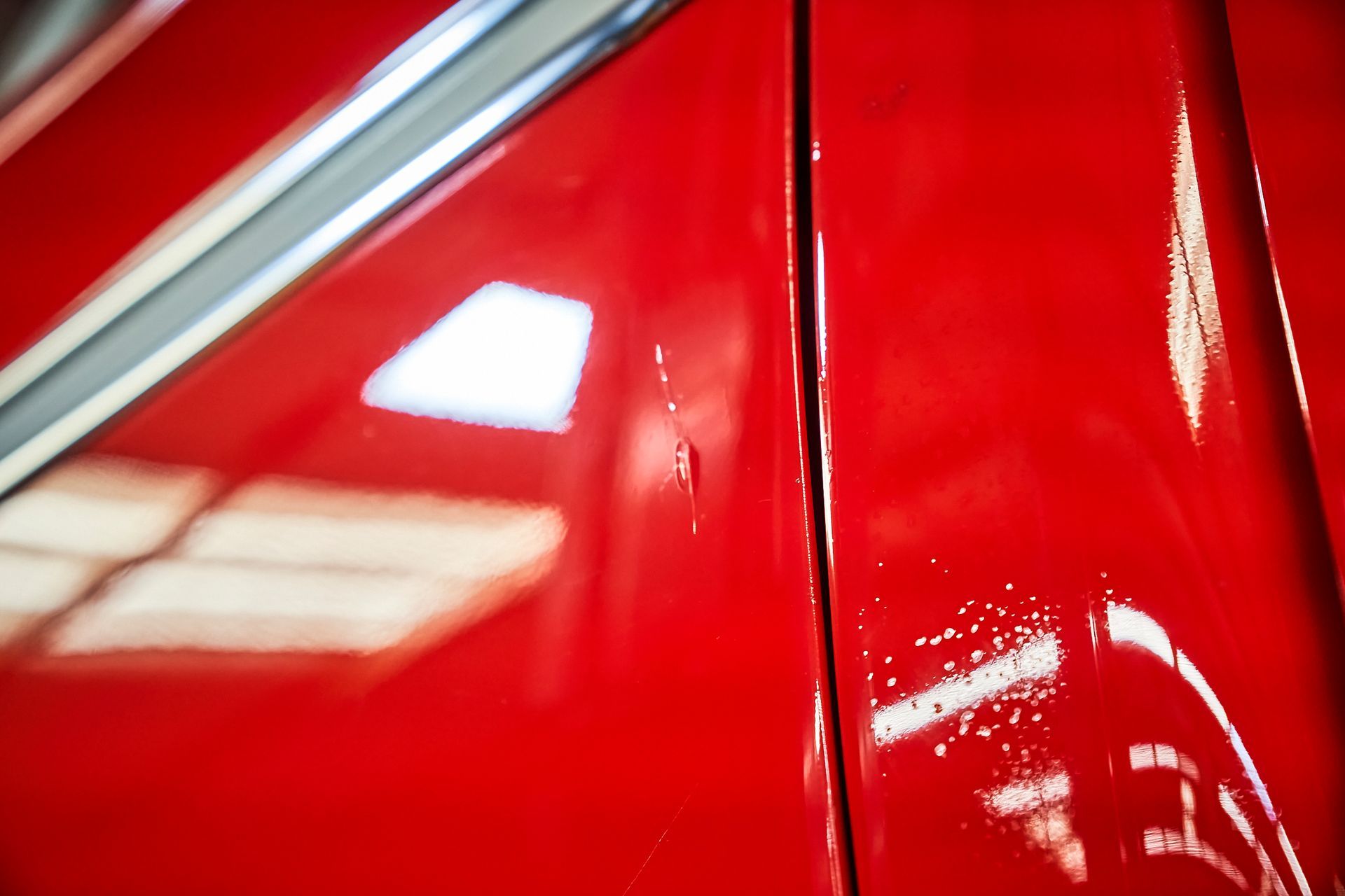 A close up of a red car with a scratch on the side.