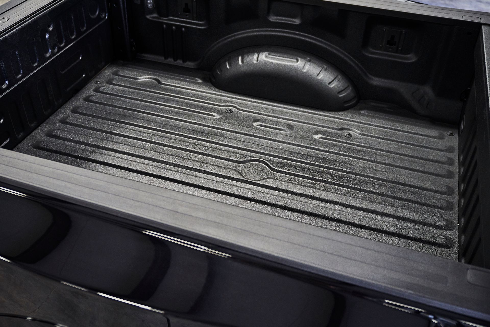 A black truck bed with a rubber mat on it