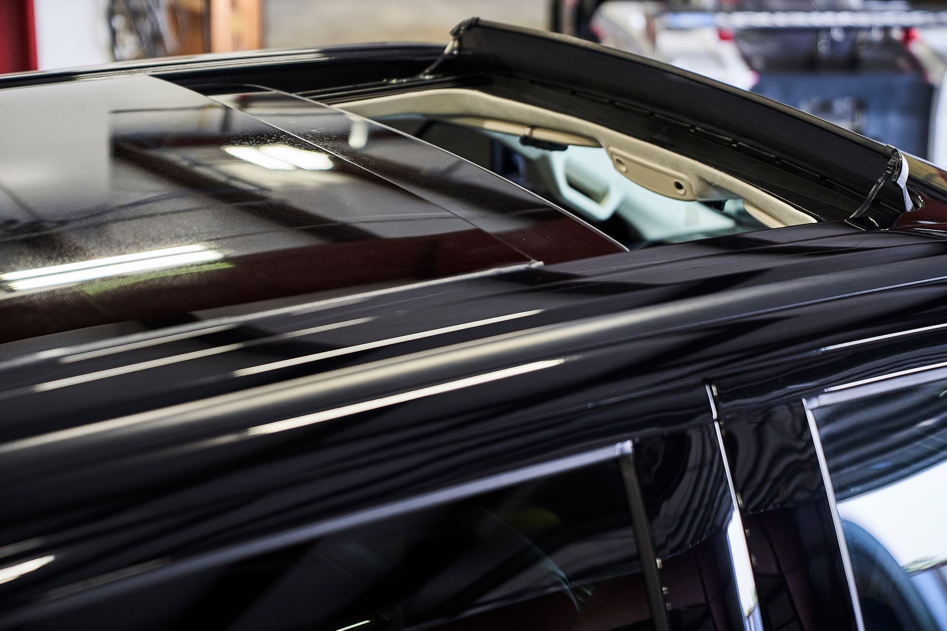 A black car with the sunroof open in a garage.