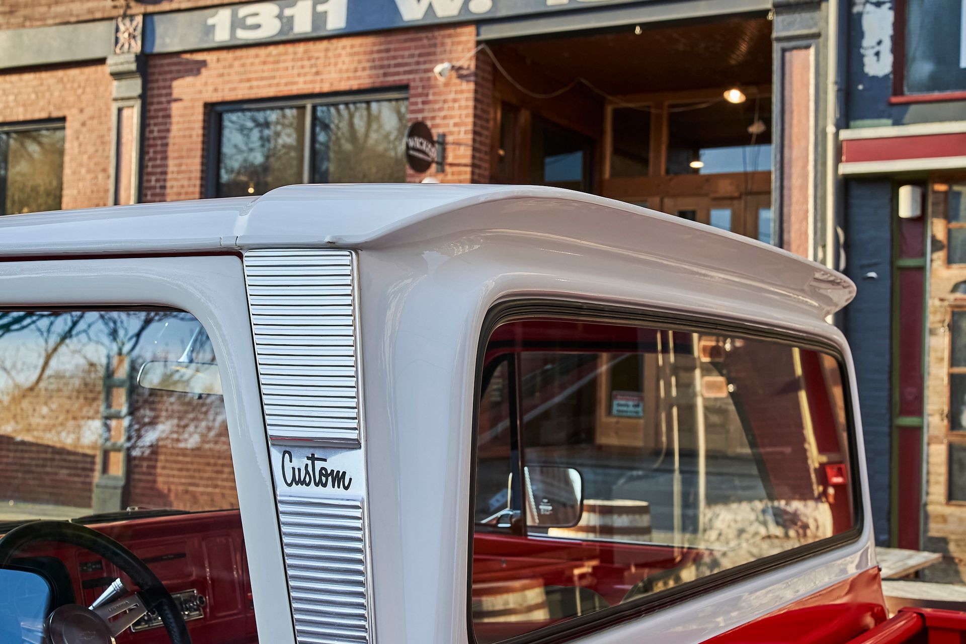 A red and white truck is parked in front of a brick building.