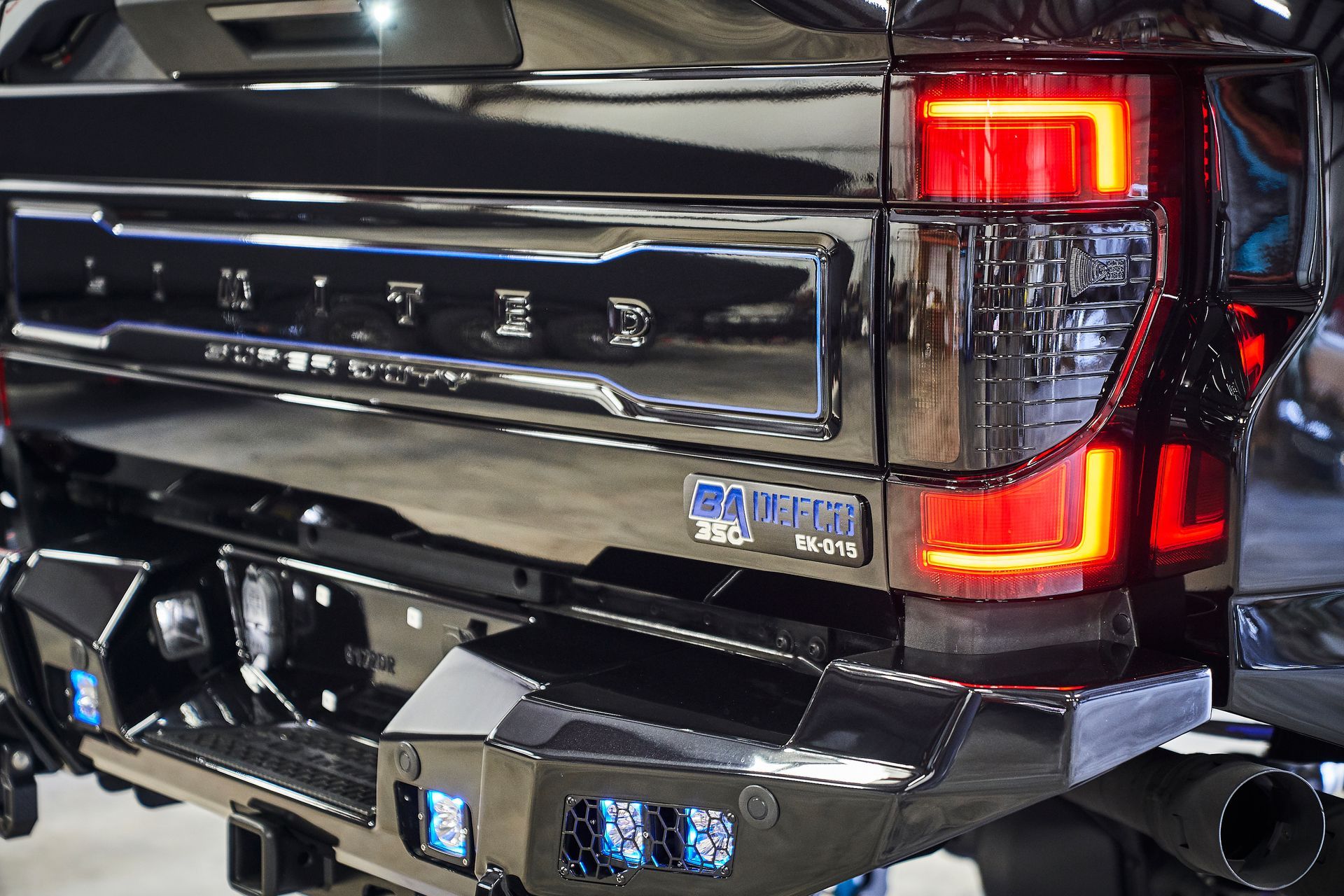 A black truck with a red tail light is parked in a garage.