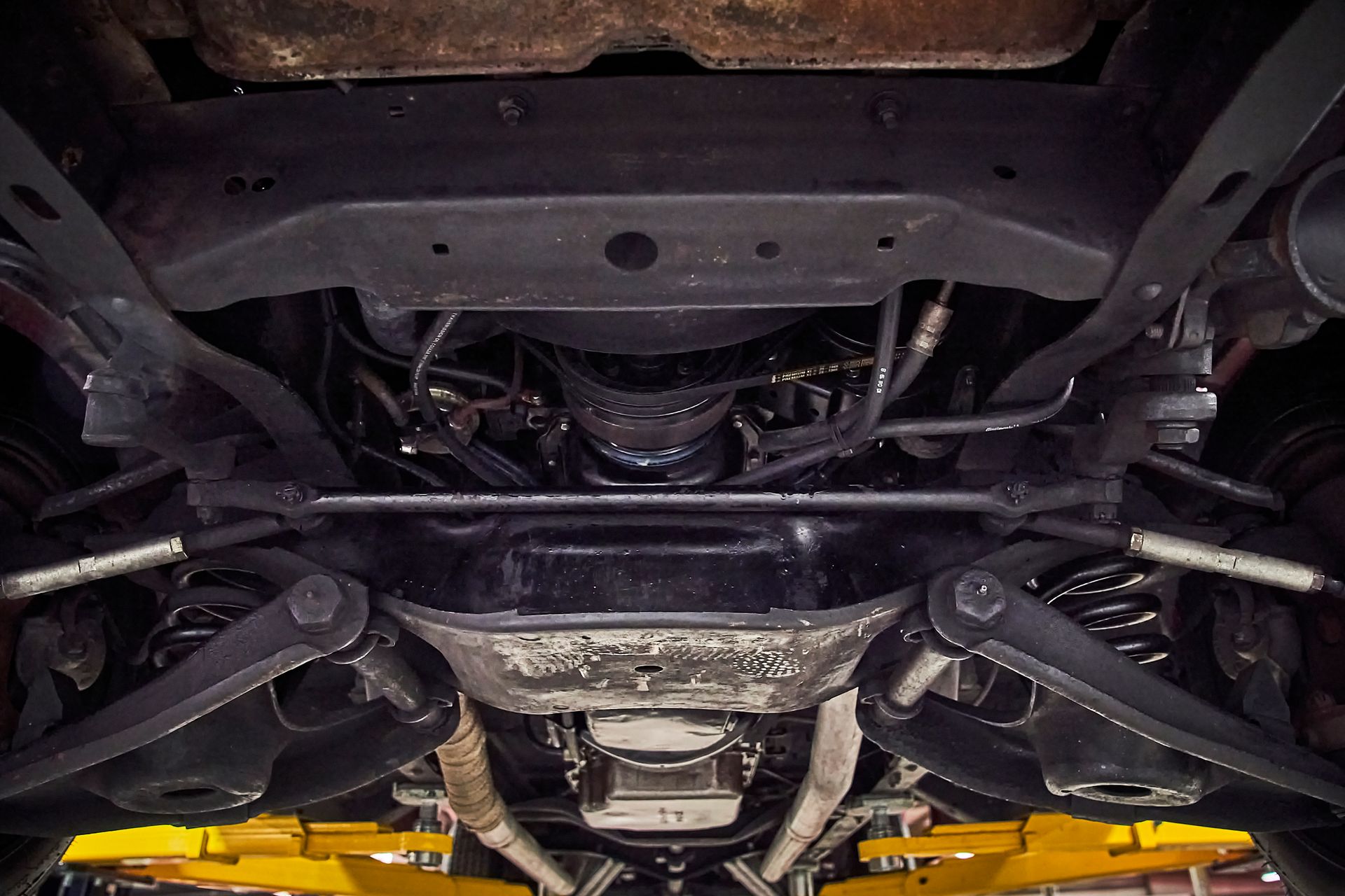 A close up of the underside of a car on a lift.