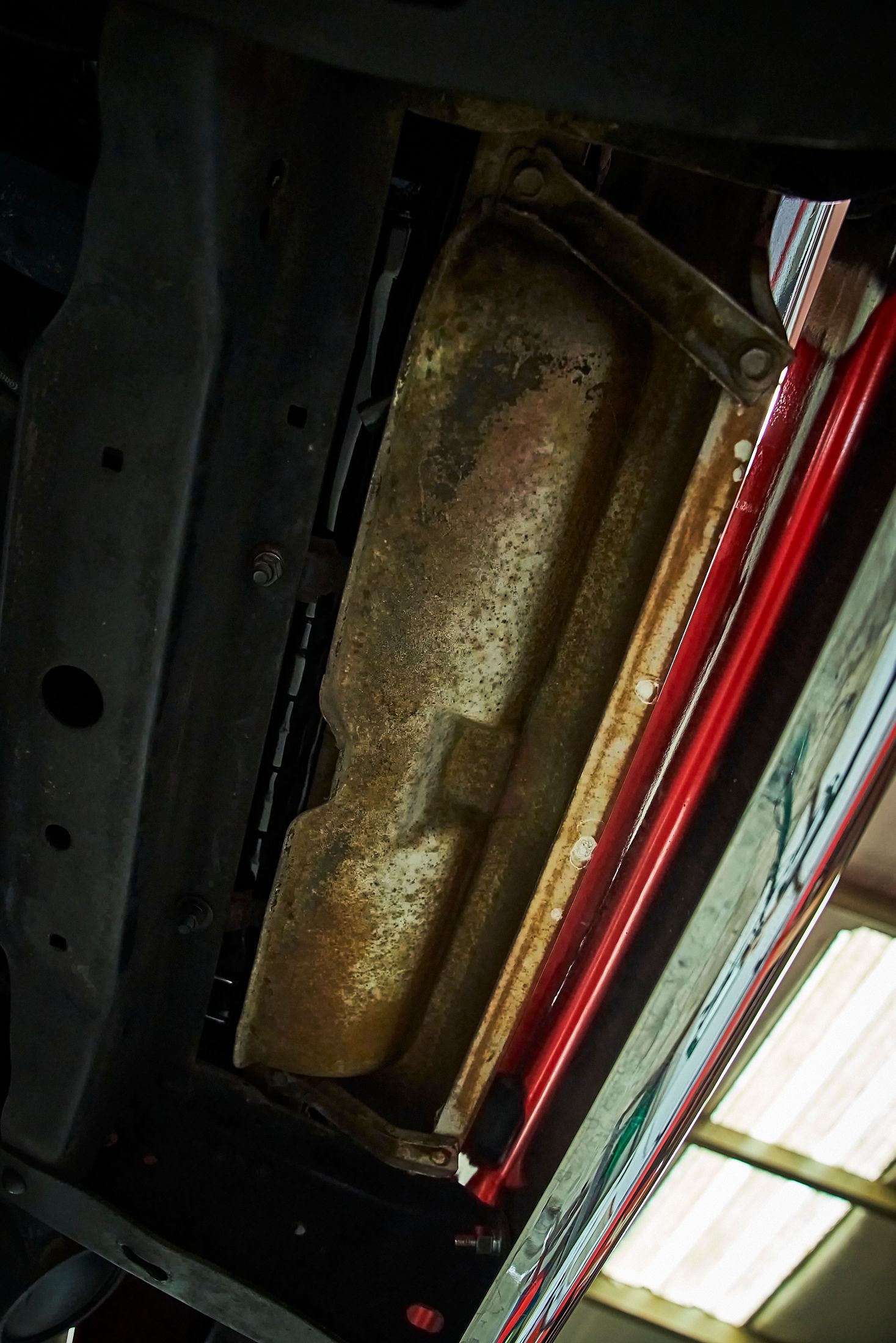 A close up of a fuel tank under a car in a garage.