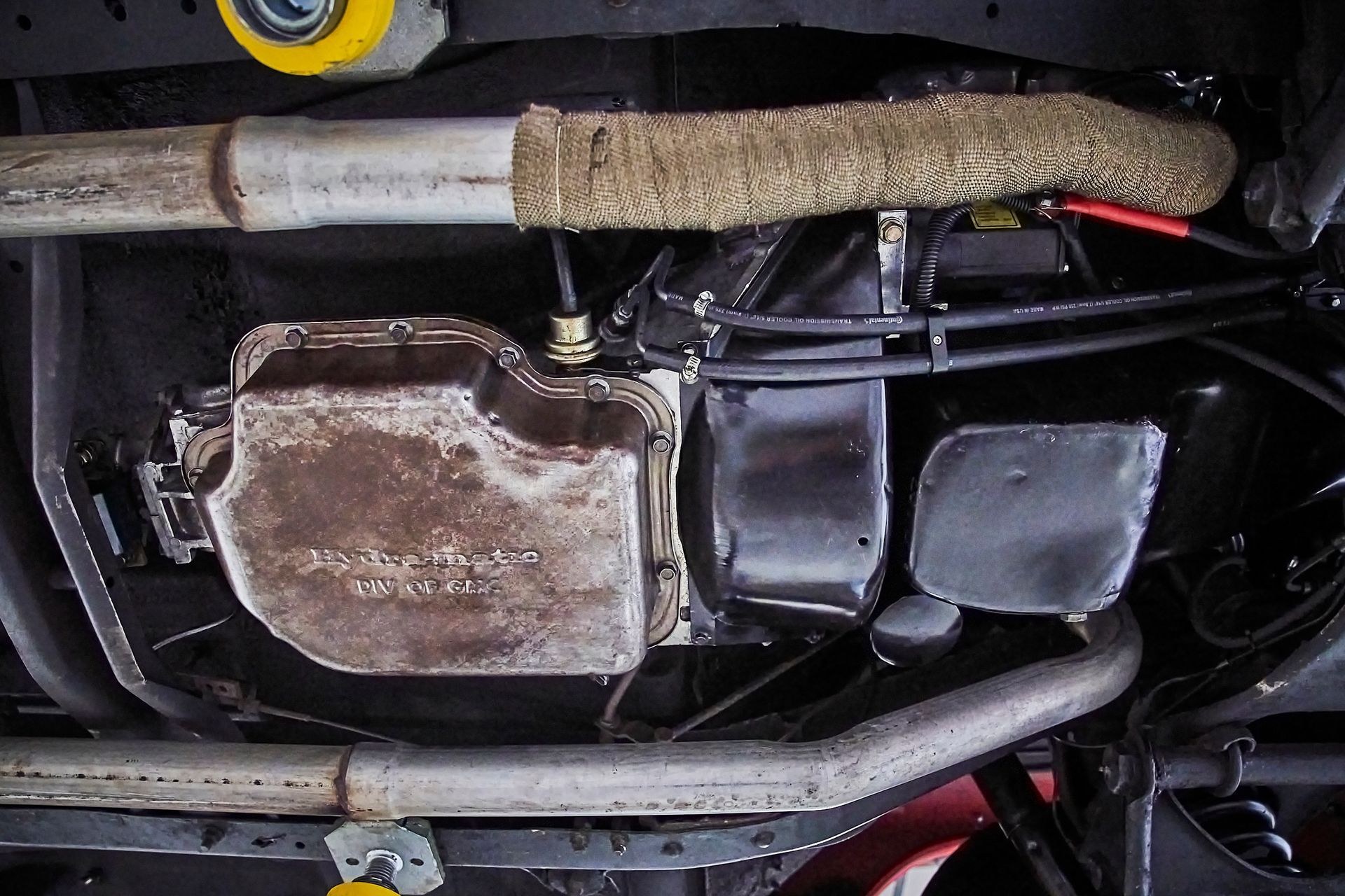 A close up of the underside of a car showing the engine and exhaust pipes