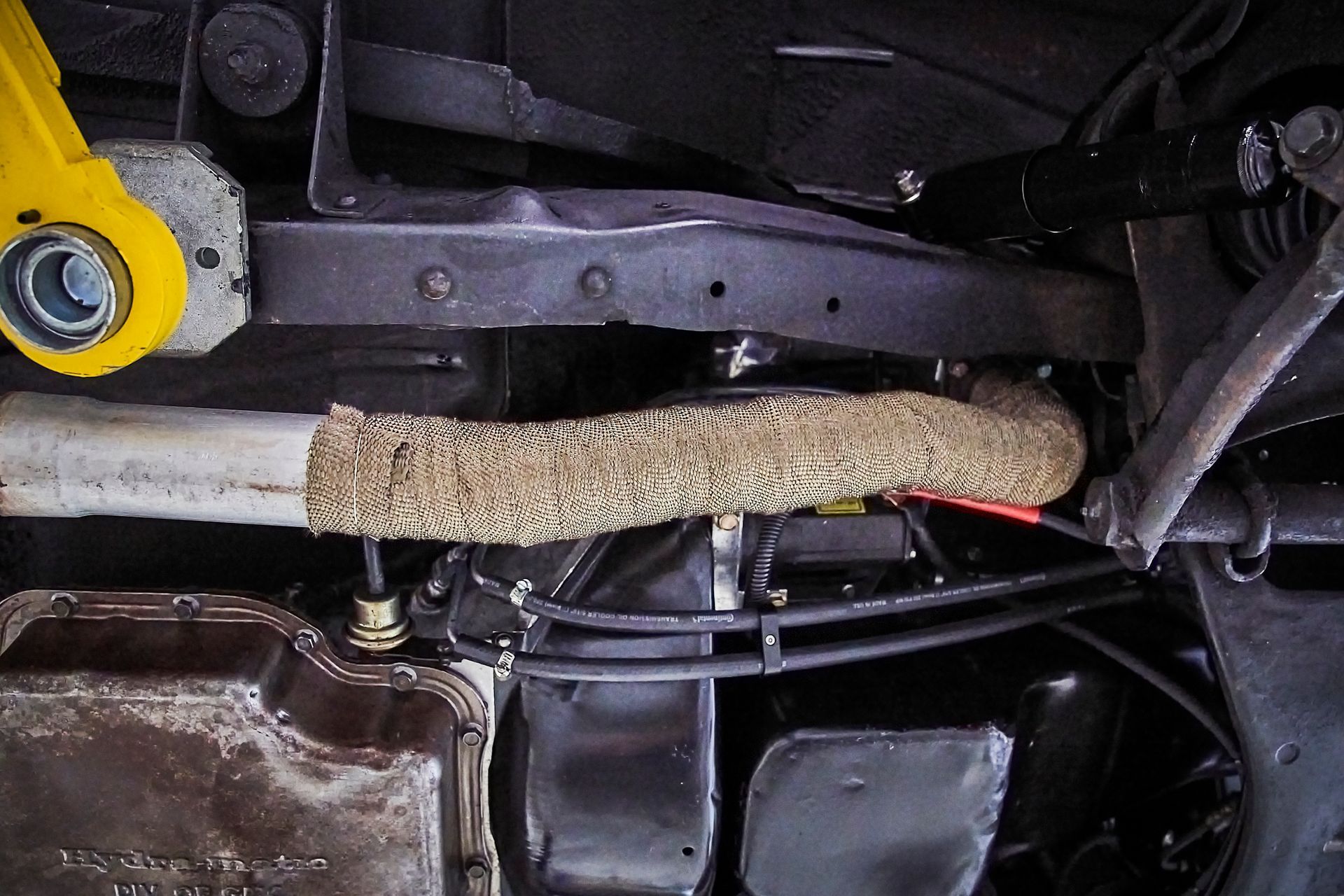 A close up of the underside of a car with a yellow wrench.
