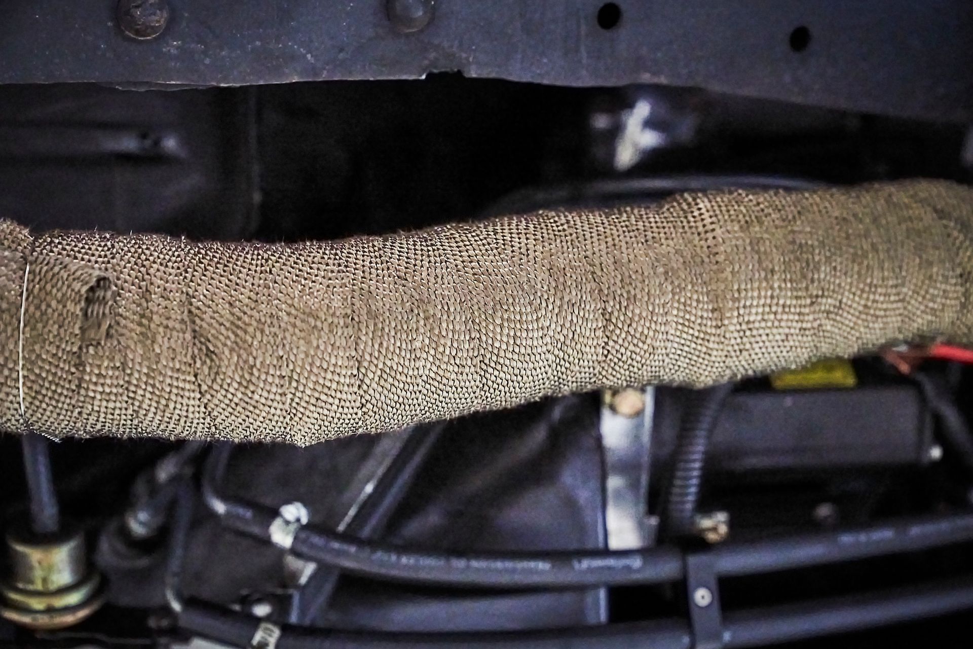 A close up of a hose on the underside of a car.