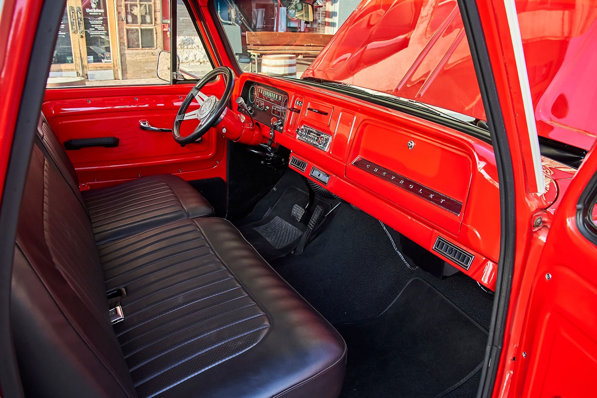 The interior of a red truck with black seats and a steering wheel.