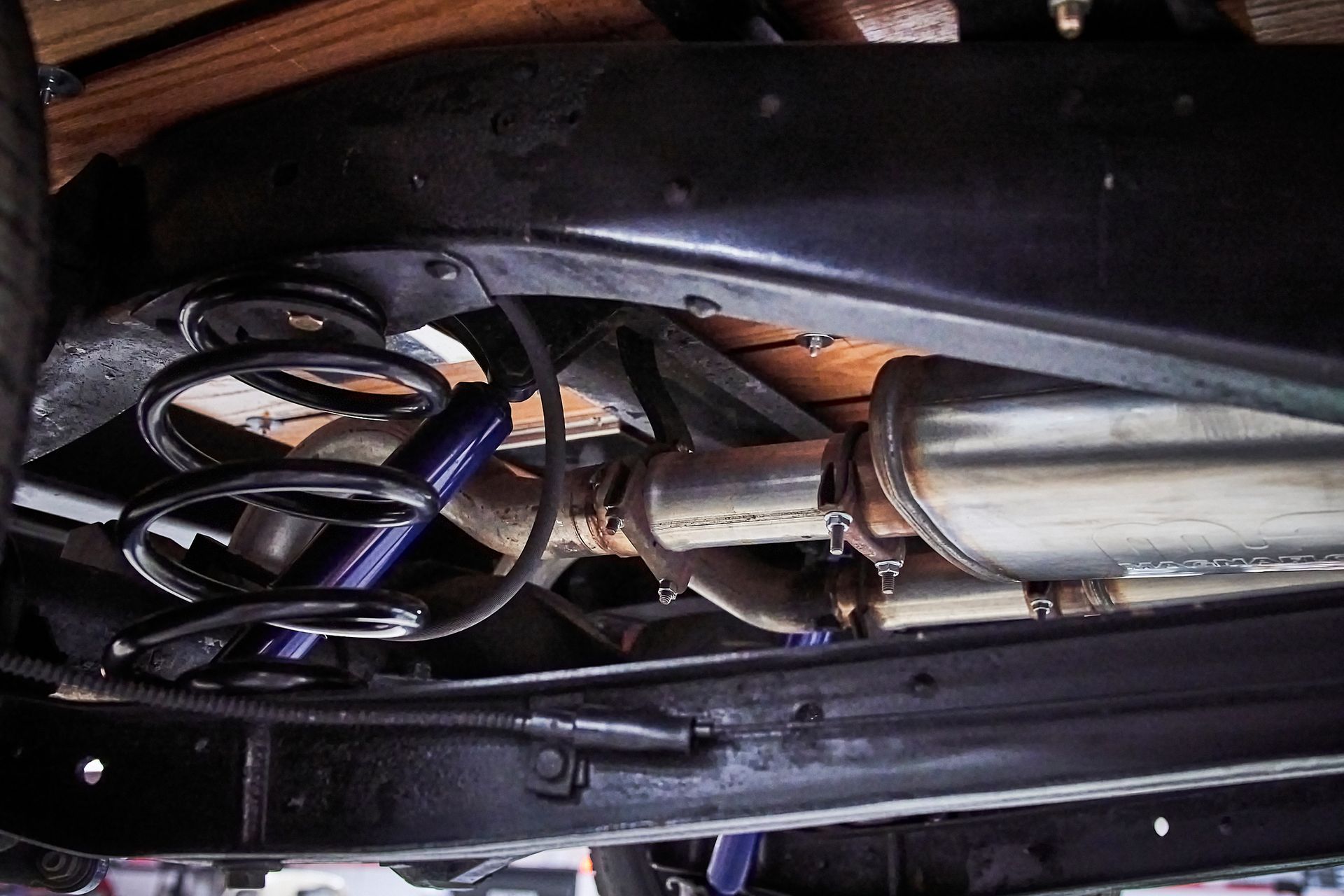 The underside of a car with a shock absorber and exhaust pipe