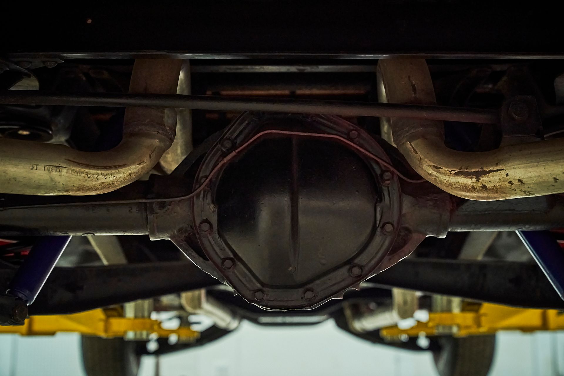 A close up of the underside of a car on a lift.