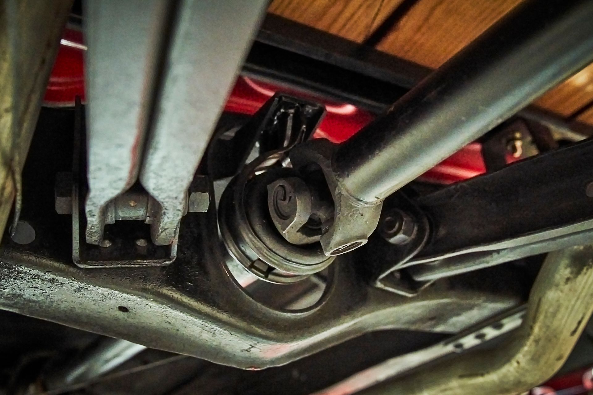 A close up of the underside of a car with a wooden floor.