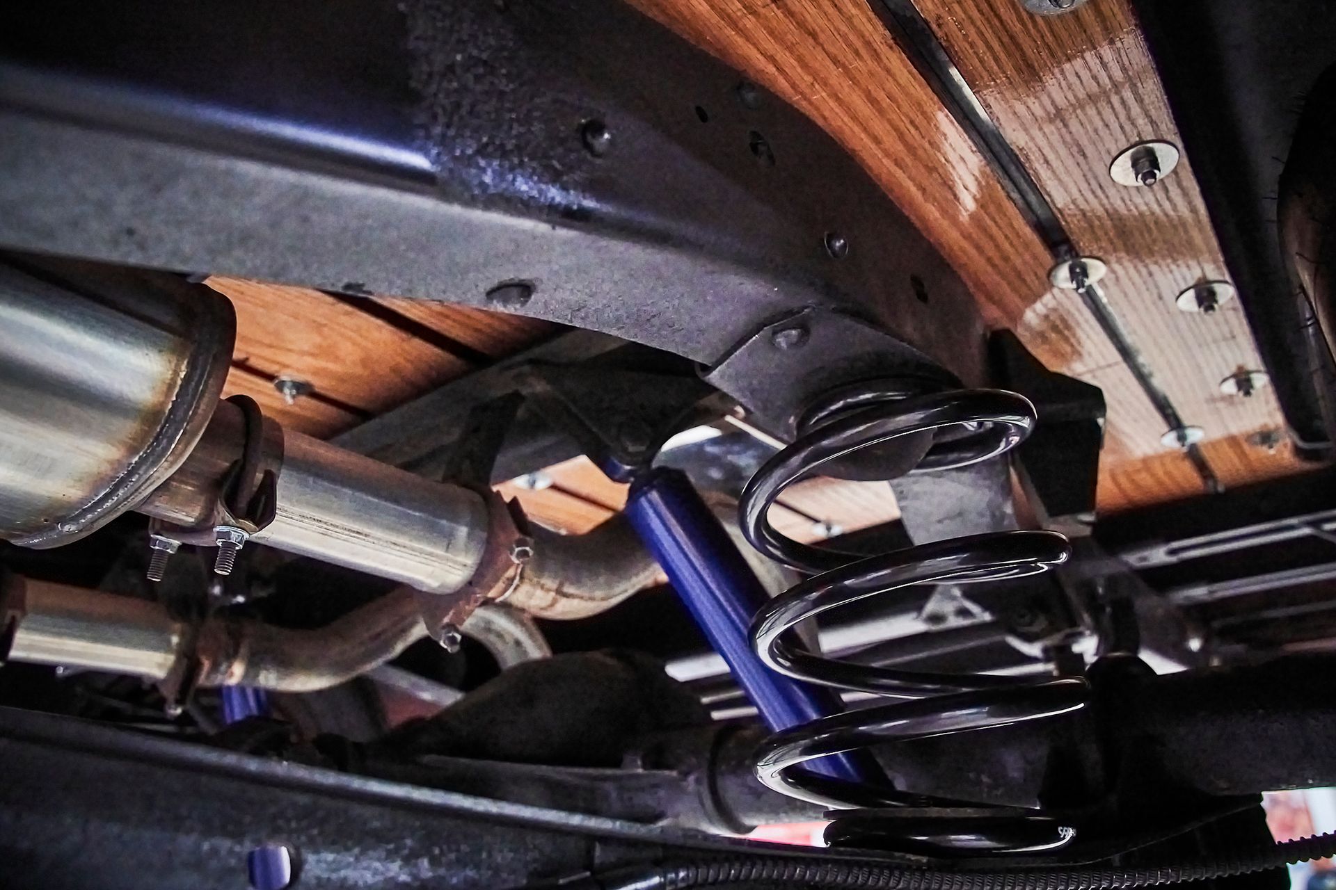 A close up of the underside of a car with shocks and exhaust pipes