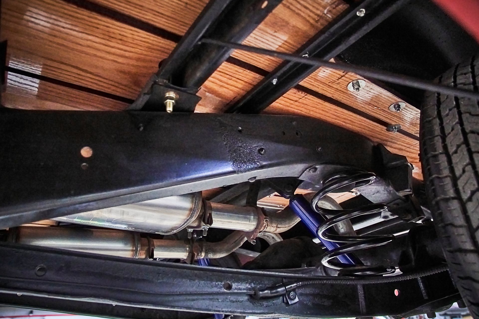 The underside of a truck with a wooden bed and exhaust pipes