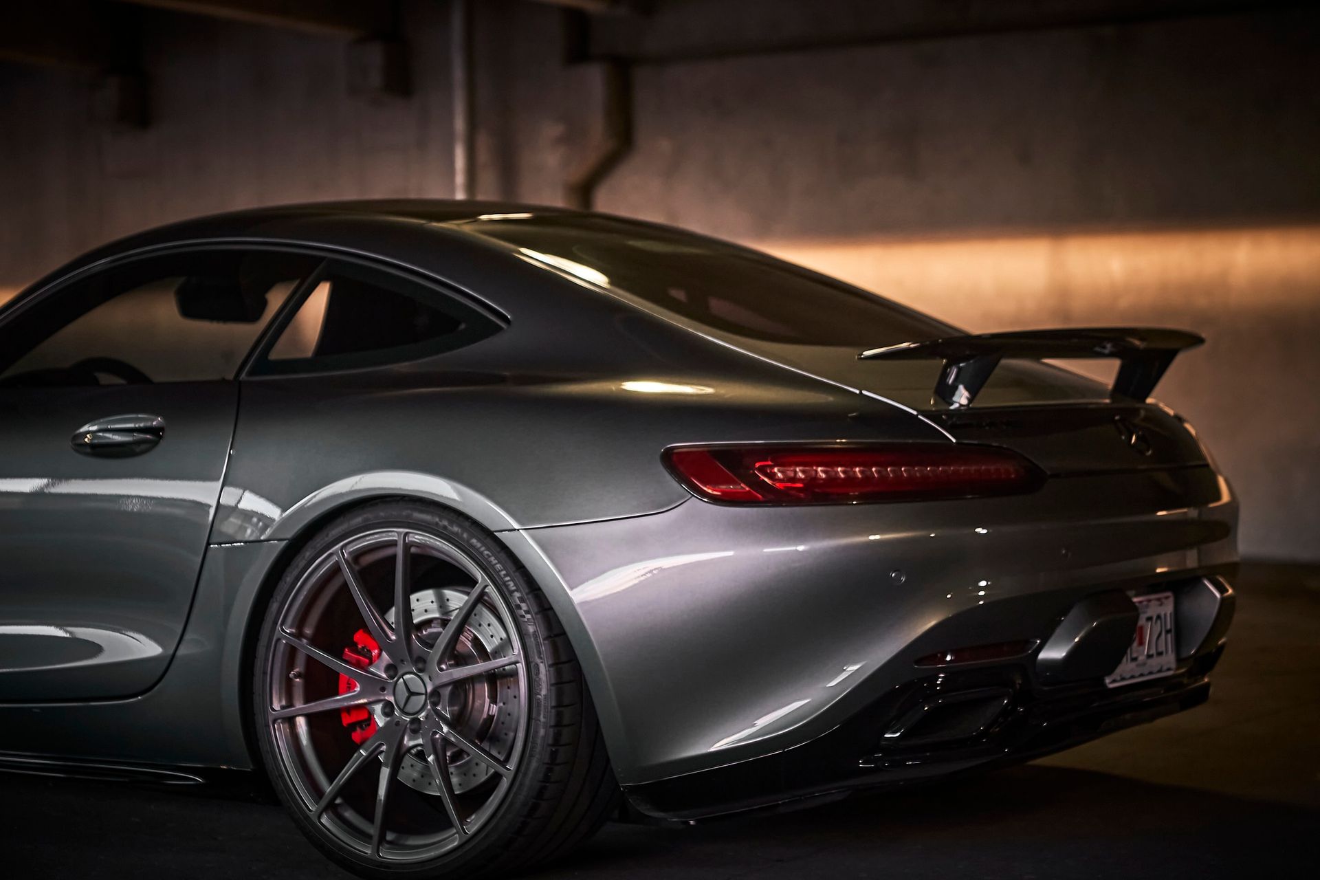 A gray sports car is parked in a dark garage.