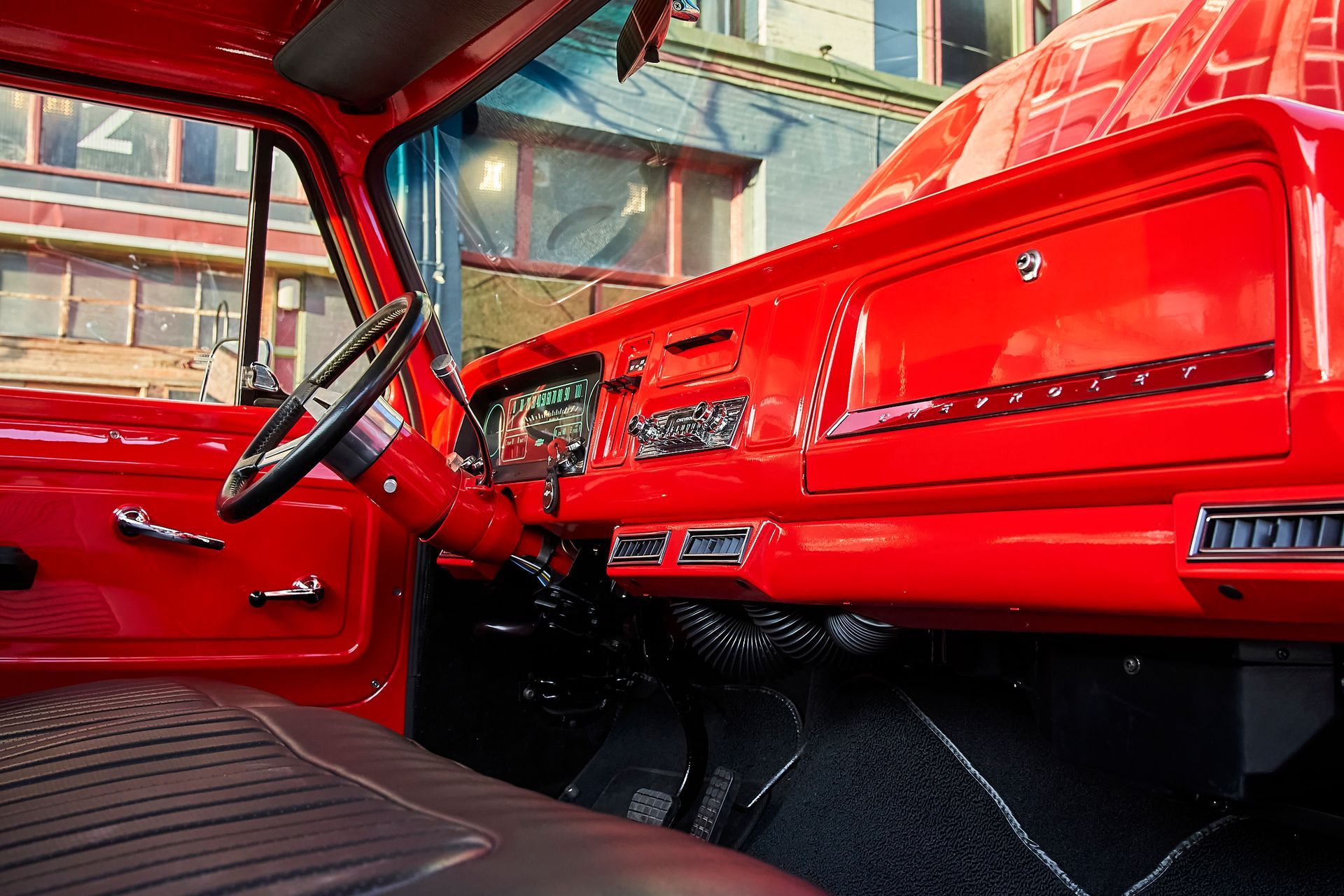 The interior of a red truck with a steering wheel and dashboard
