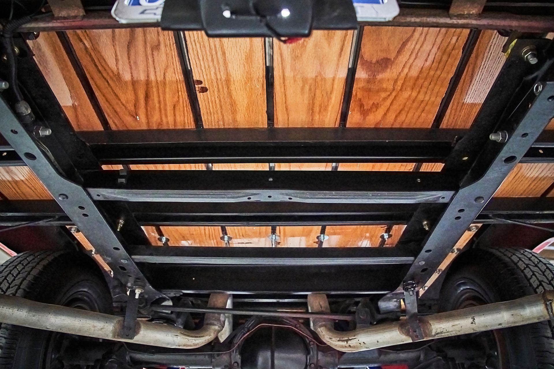 The bottom of a truck with a wooden bed and exhaust pipes.