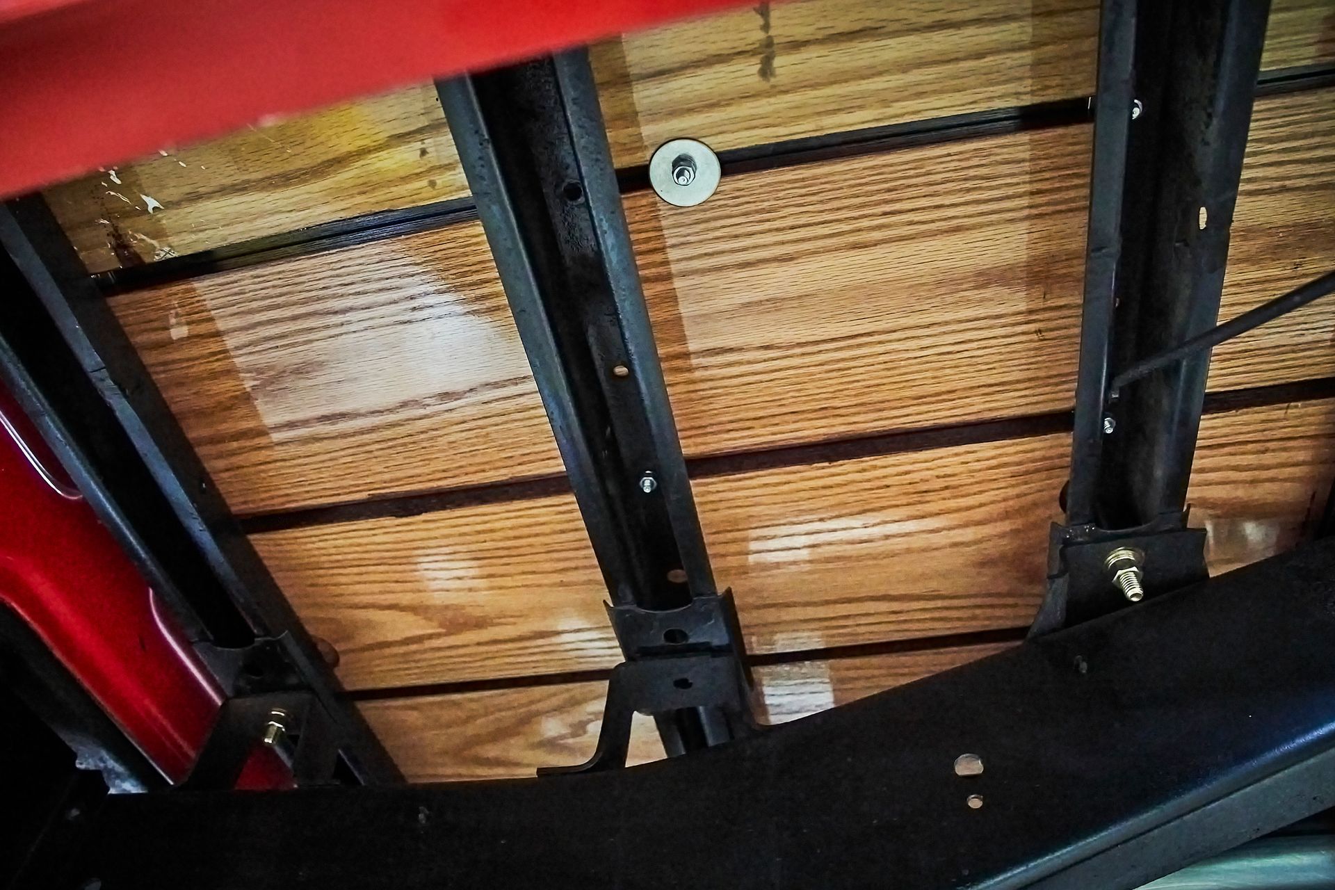 The bottom of a red truck with a wooden bed