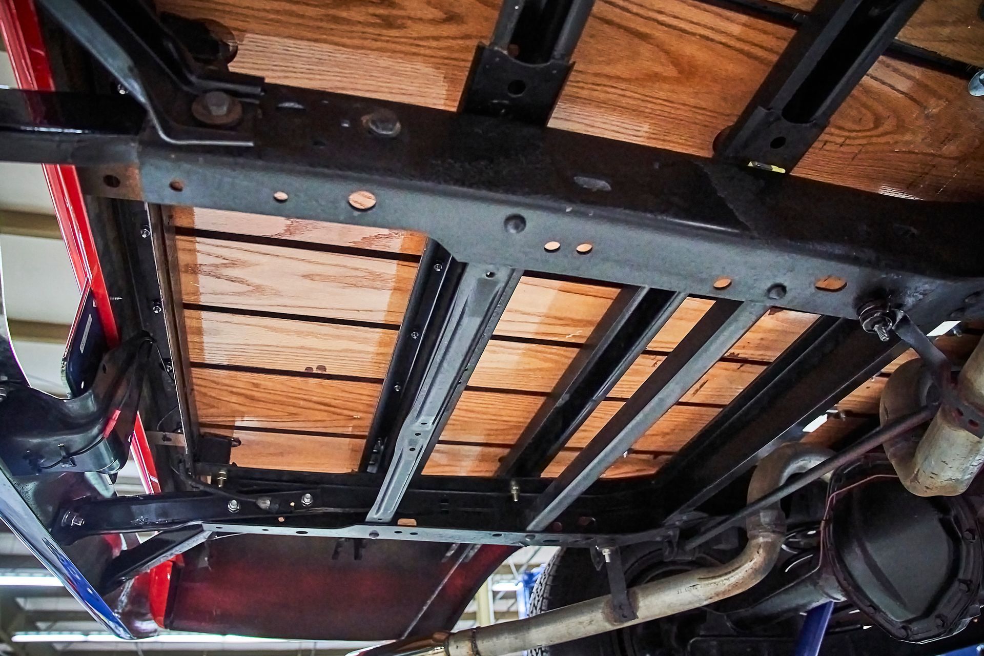 The underside of a truck with a wooden bed.