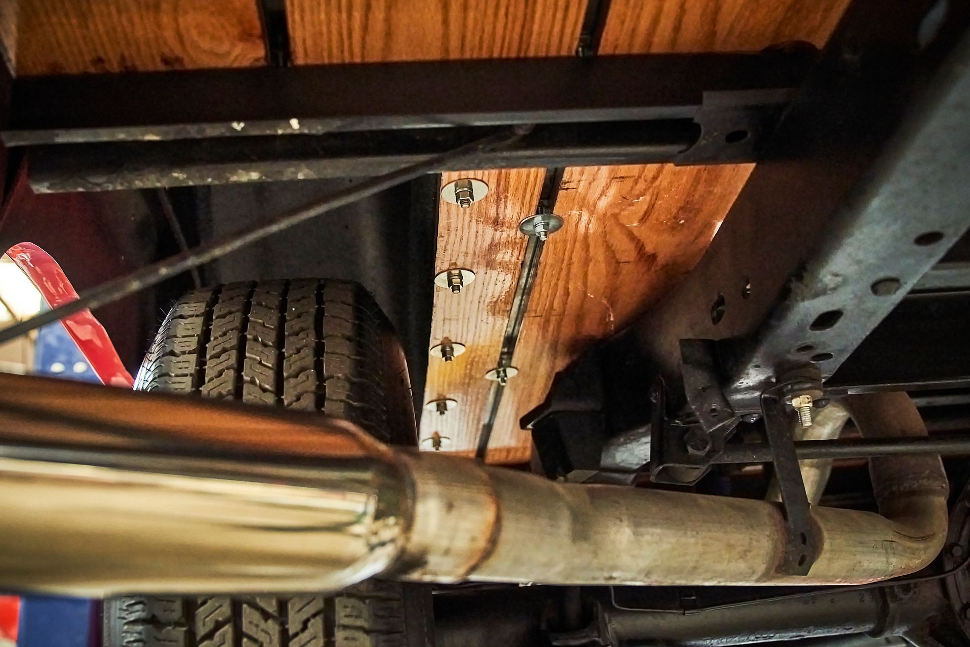 A close up of the underside of a truck with a tire and exhaust pipe.