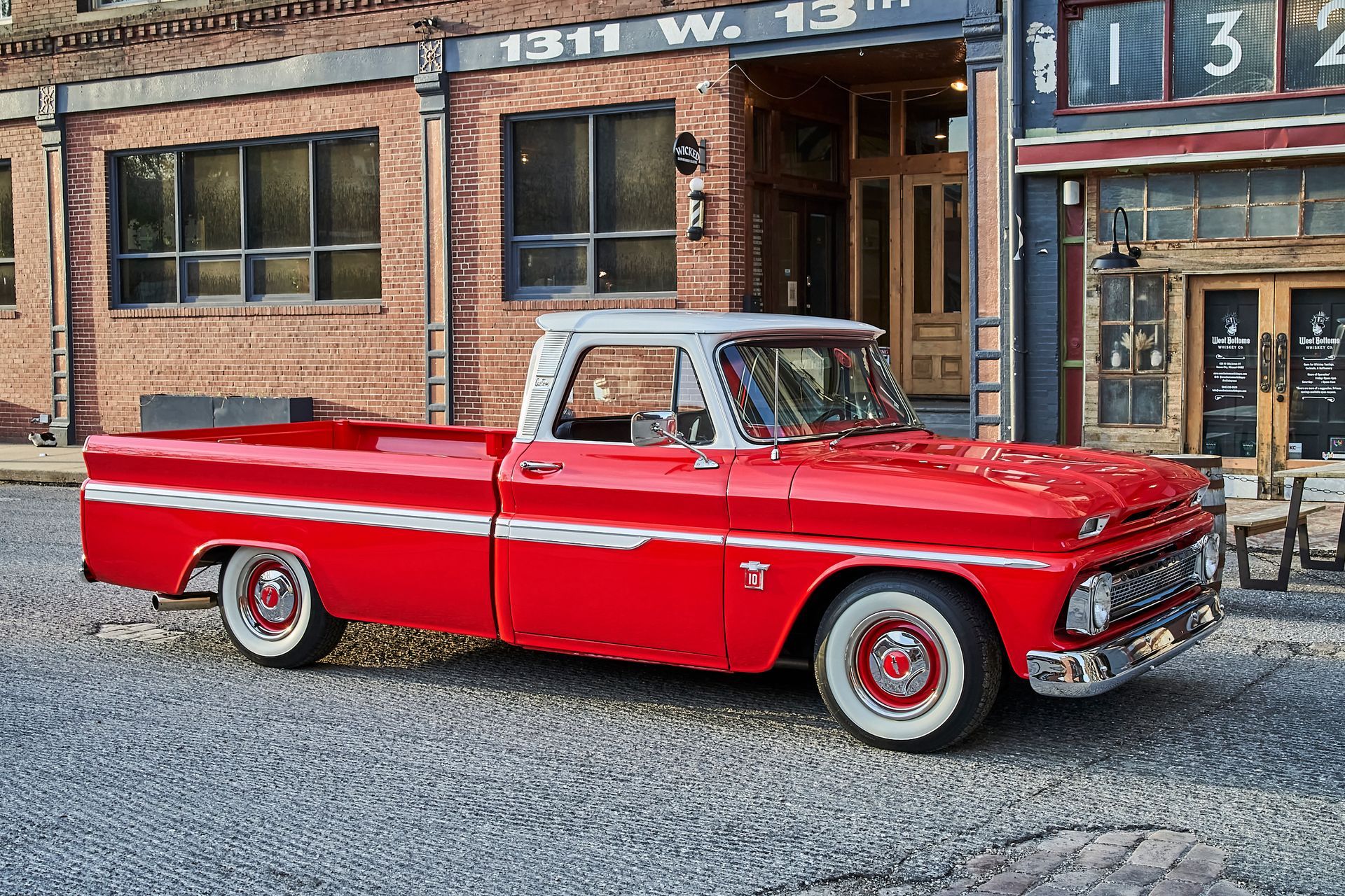 A red truck is parked in front of a brick building.