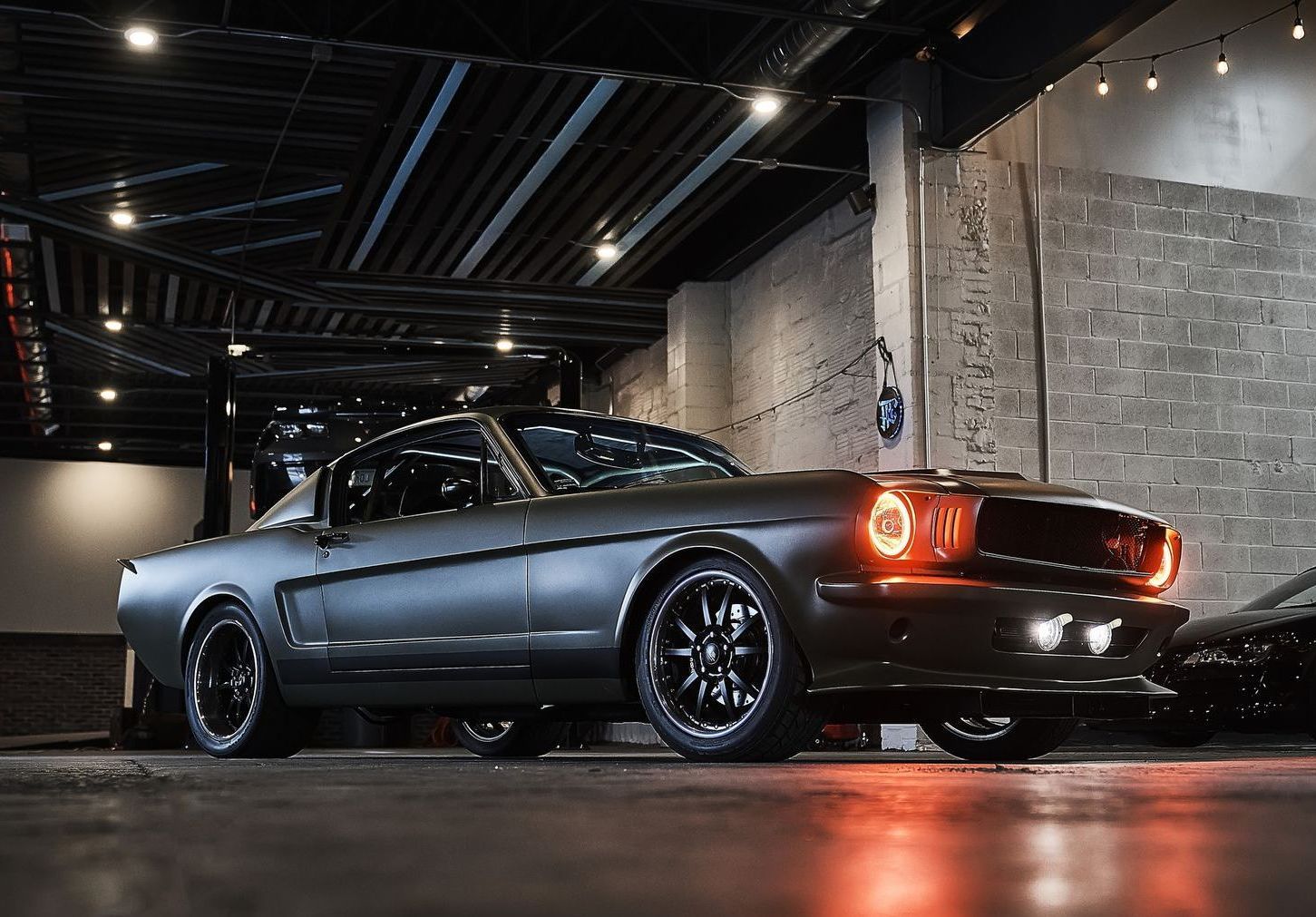 A black mustang is parked in a garage.