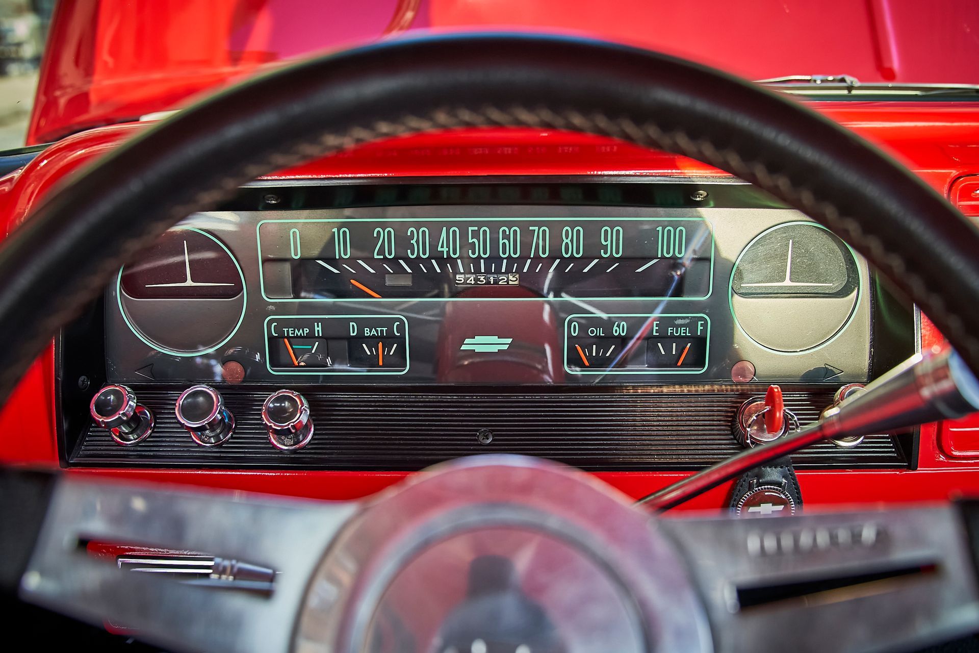 A close up of a red car 's dashboard and steering wheel