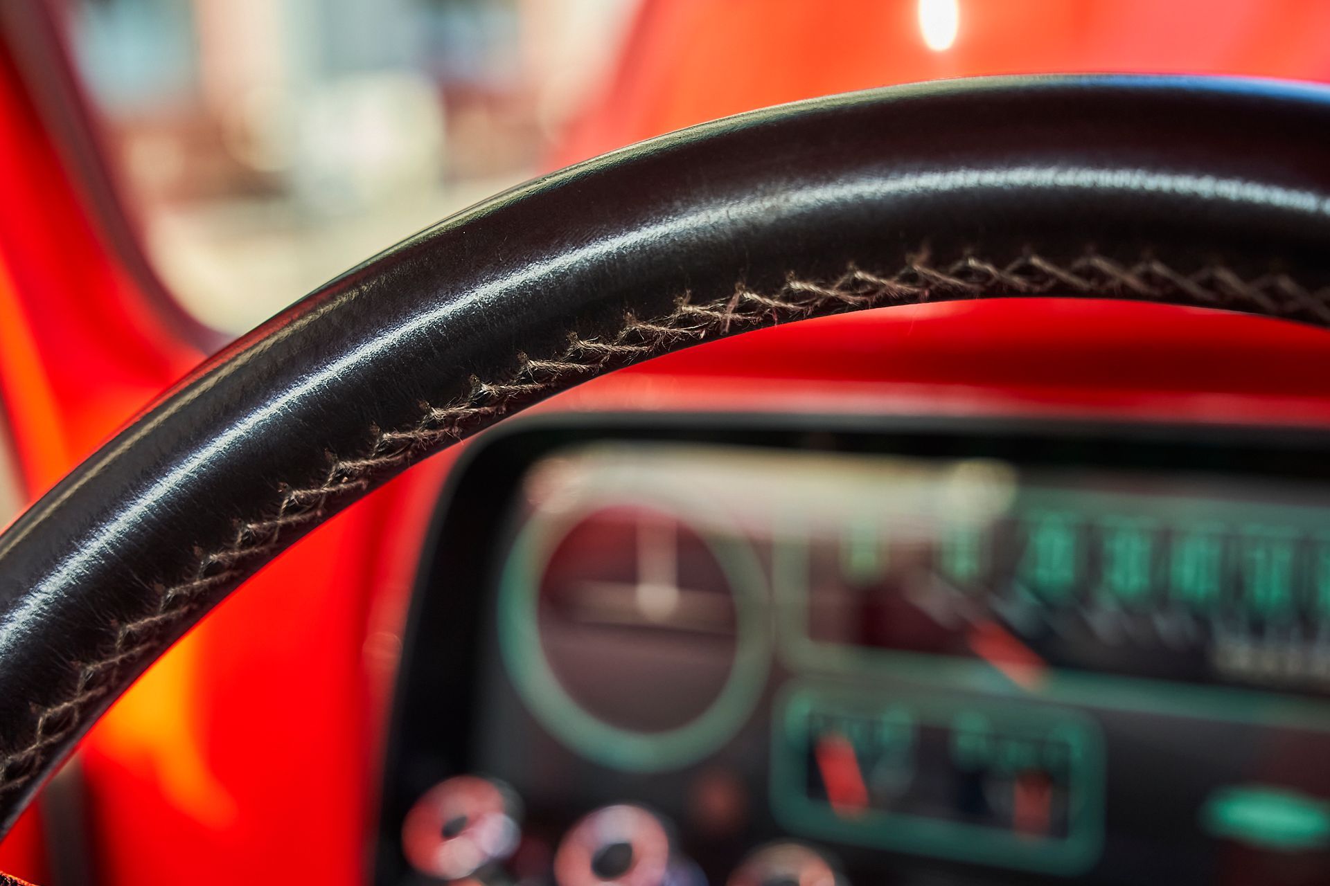 A close up of a steering wheel in a red car.