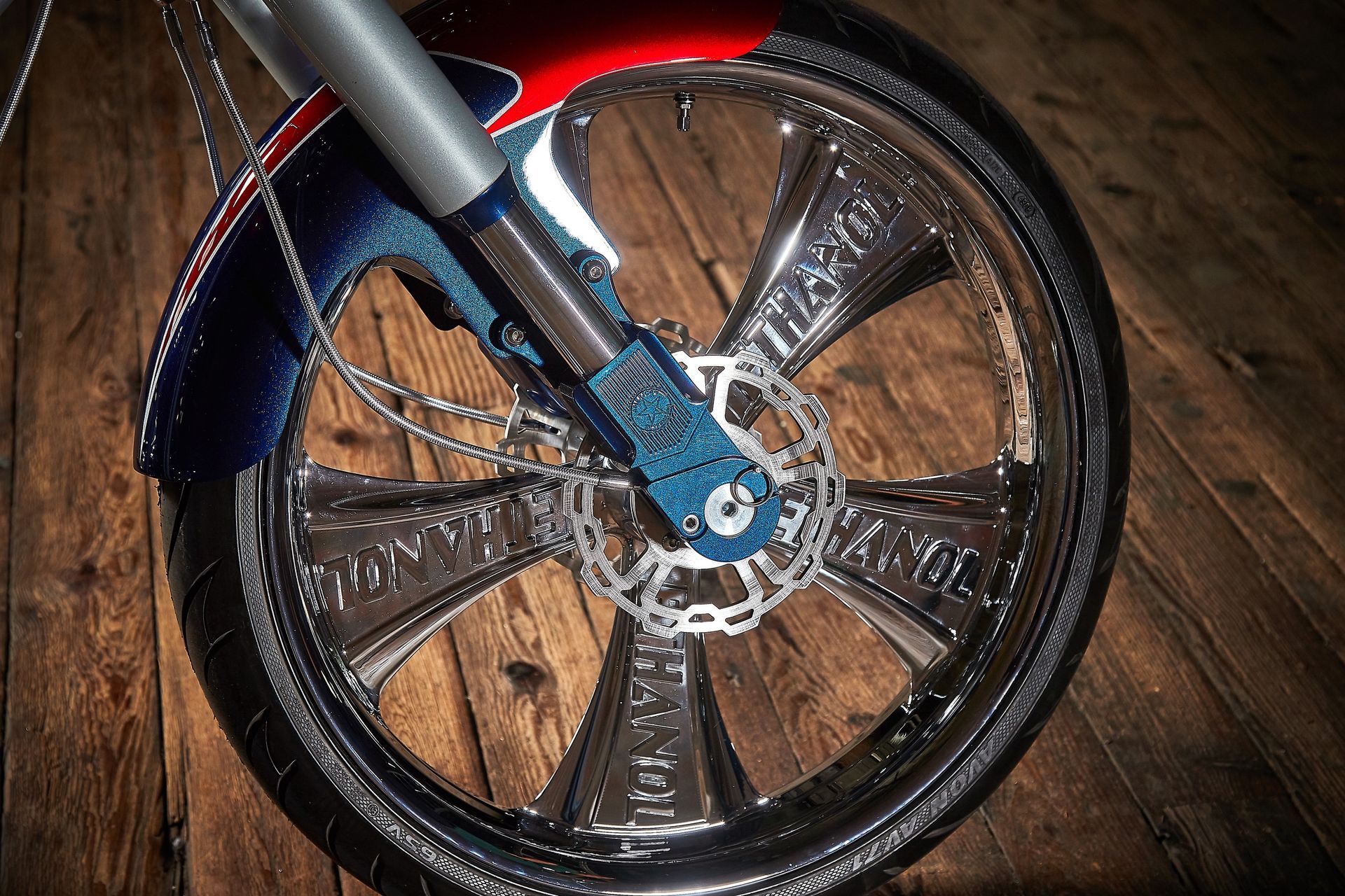 A close up of a motorcycle wheel on a wooden floor