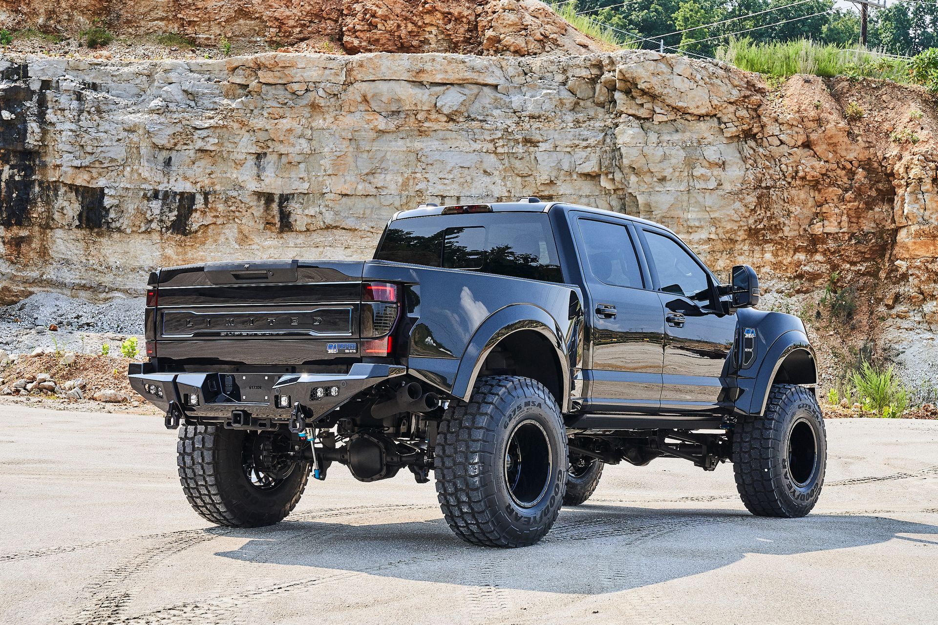 A black truck is parked in front of a rock wall.