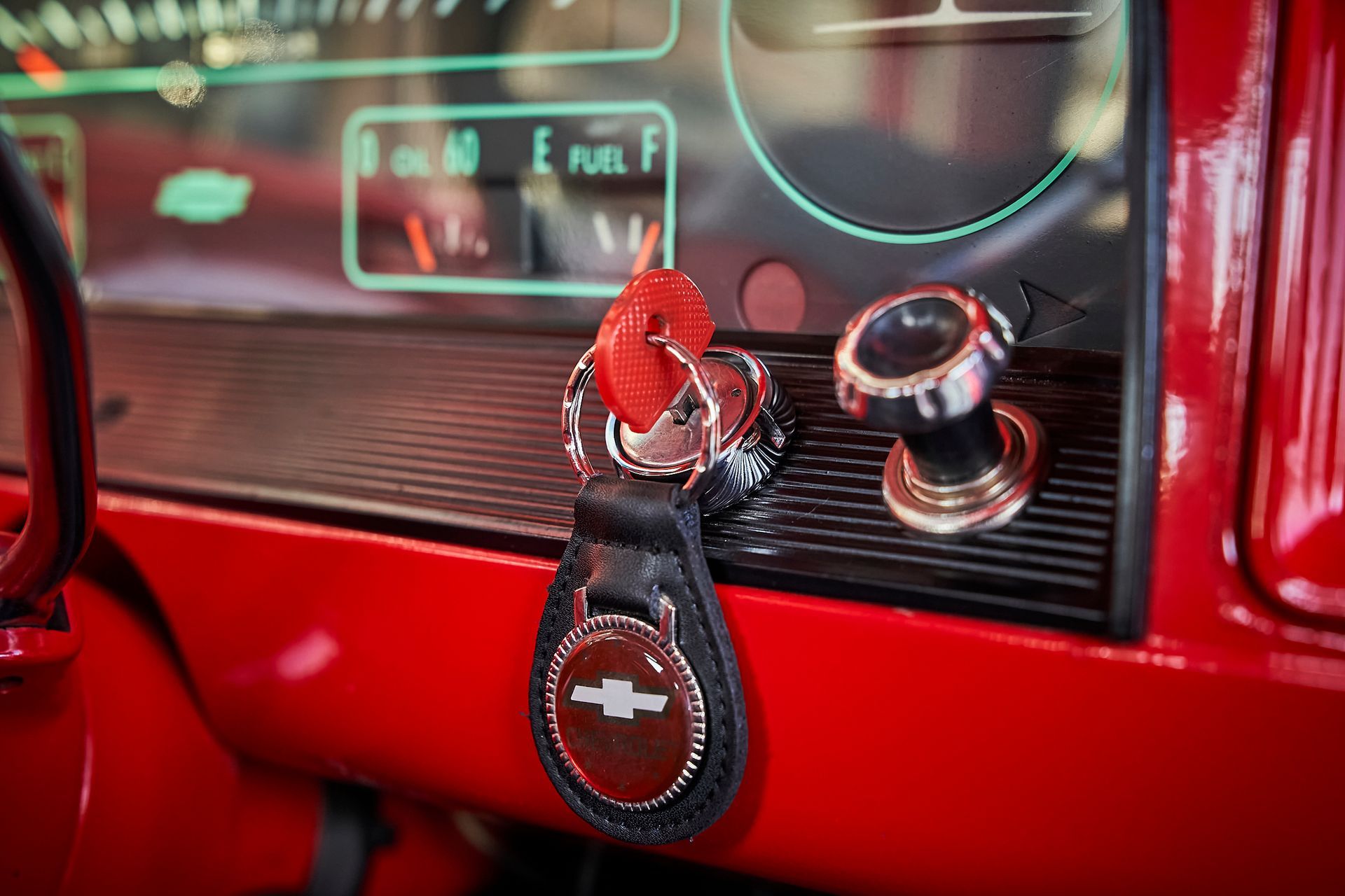 A close up of a red car dashboard with a key in it.